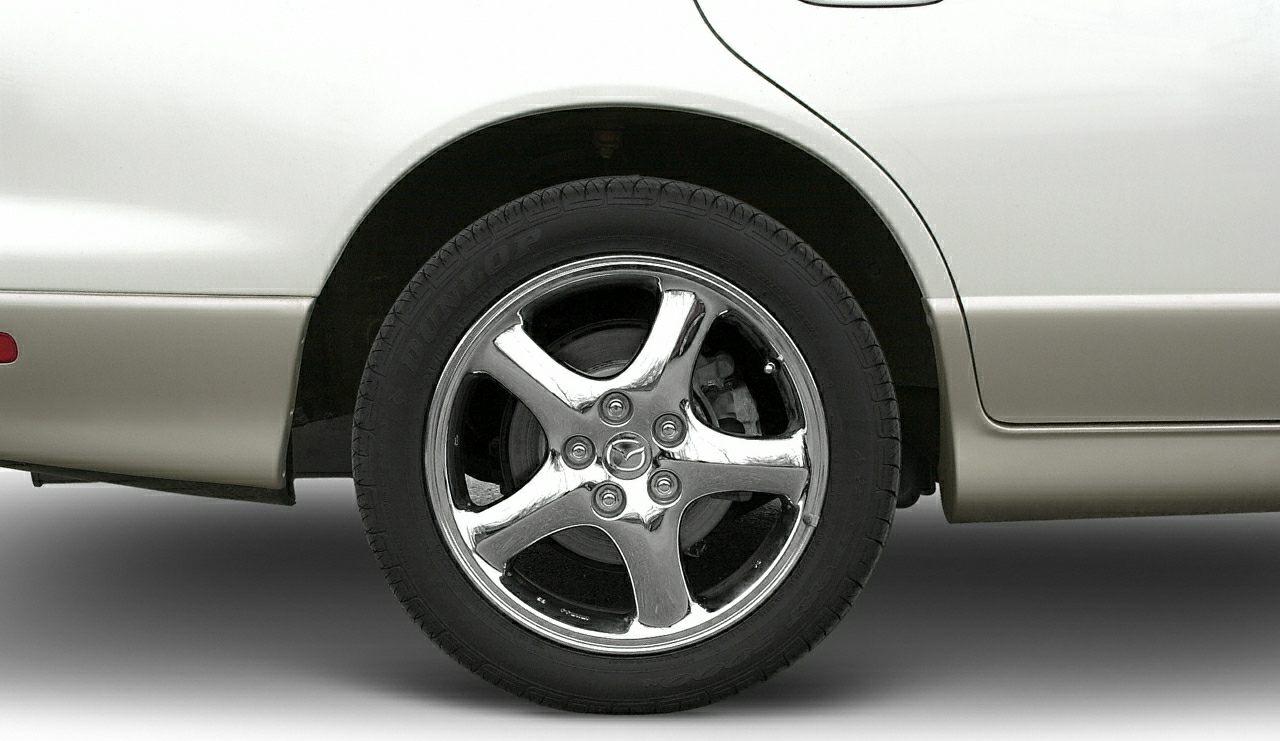 Chrome five-spoke alloy wheel and tire on sedan side panel