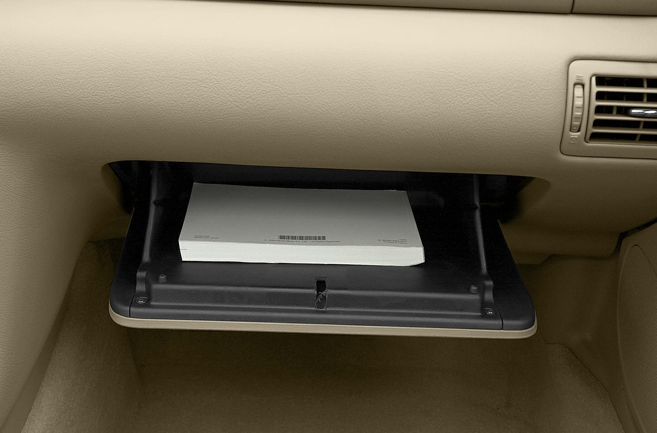 Open glove compartment with beige interior and a manual inside