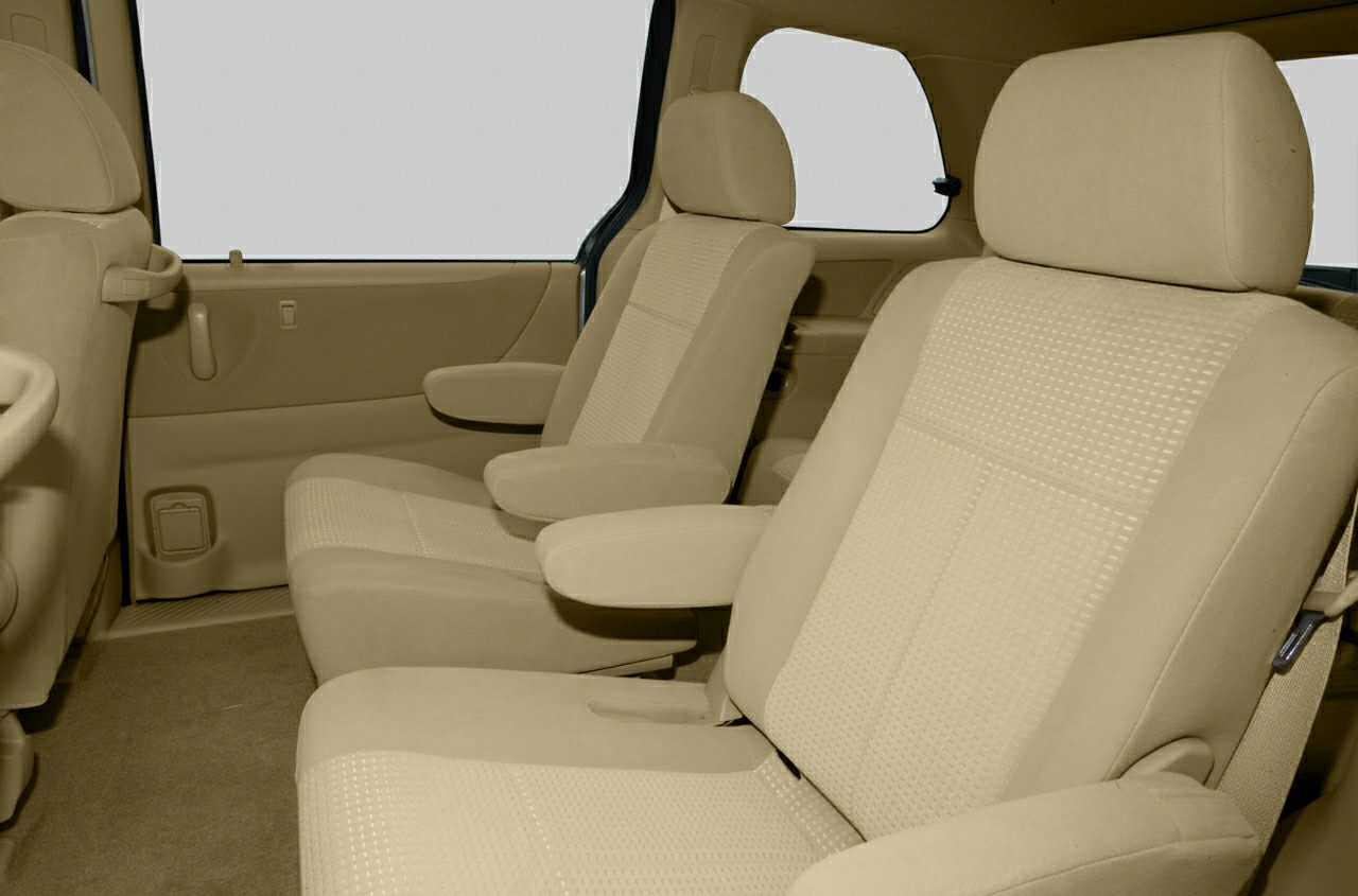 Beige fabric seats with armrests inside a minivan interior.