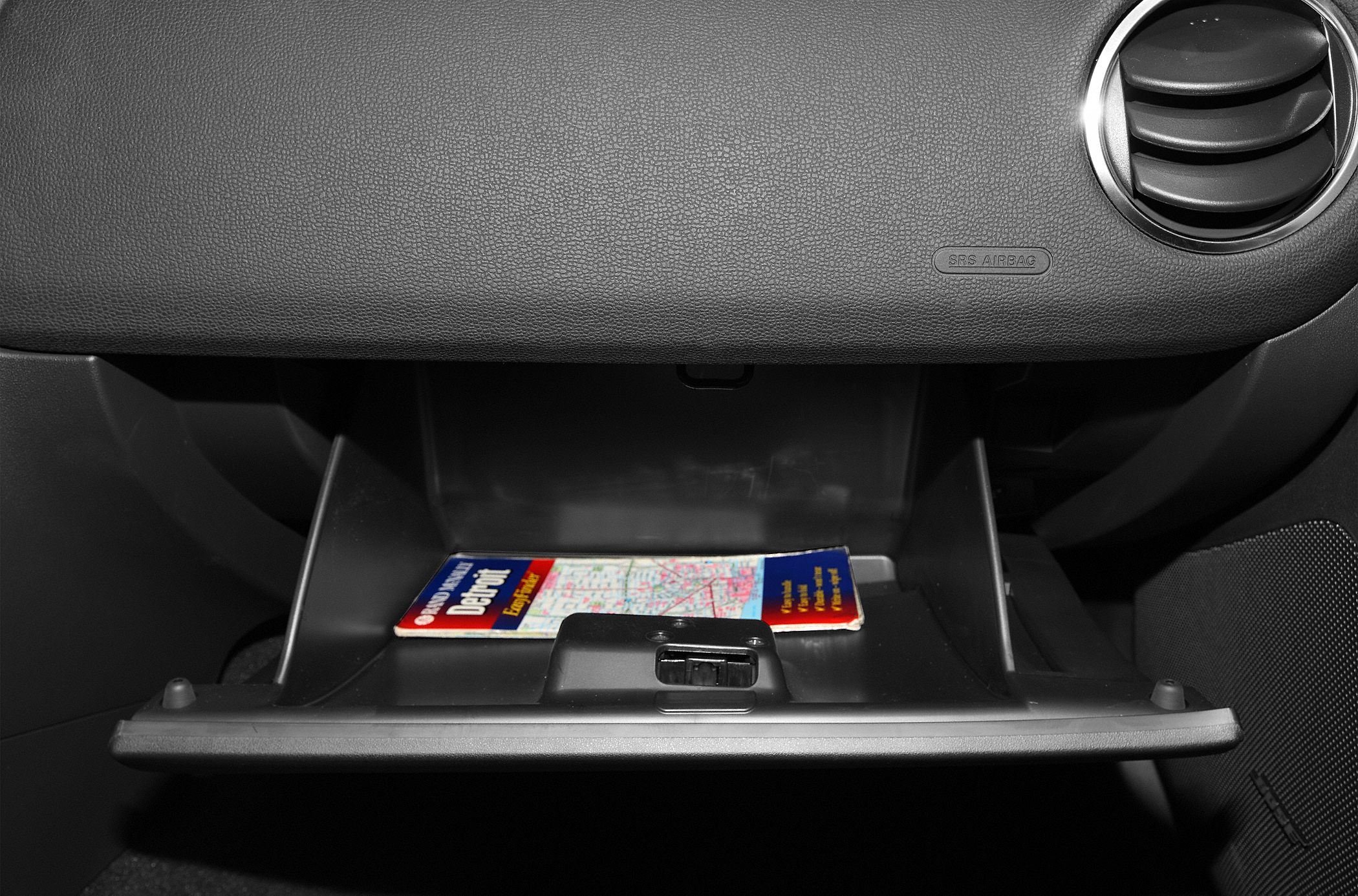 Open glove compartment with a map and circular air vent