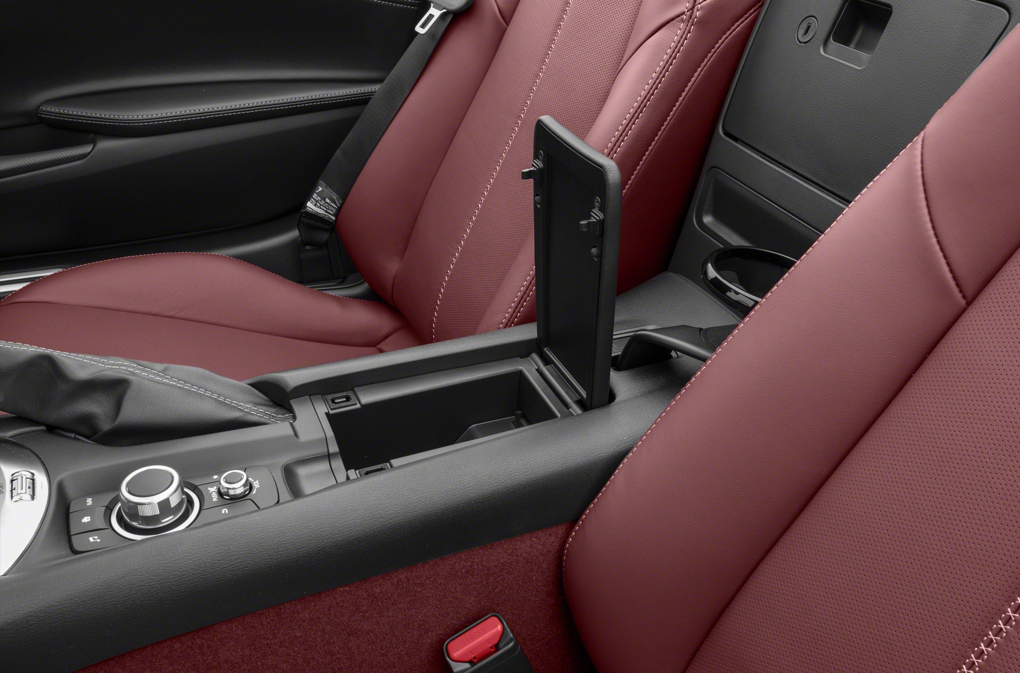 Open center console storage and control dial between red leather car seats