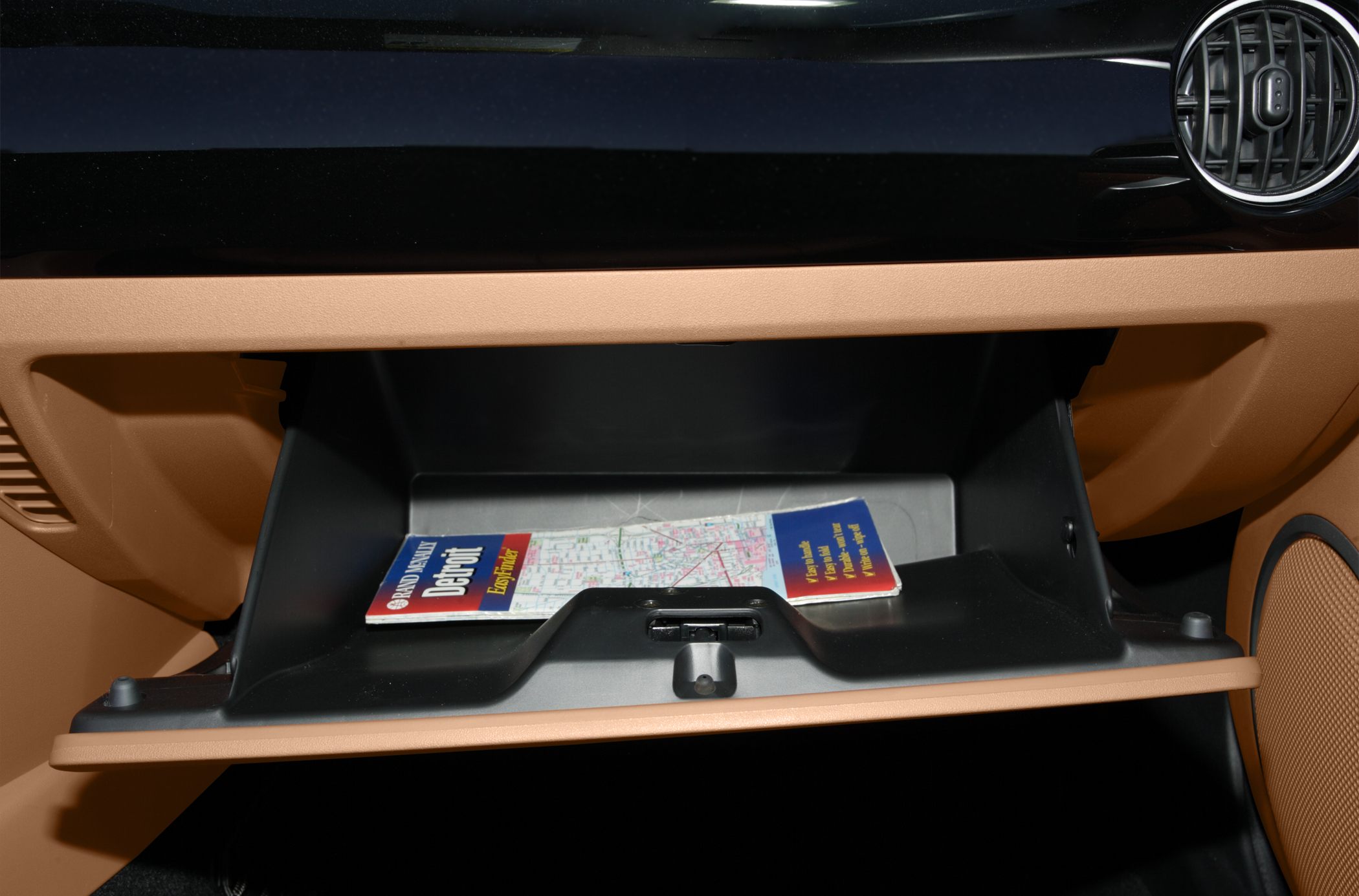 Open glove compartment with map inside in brown and black car interior