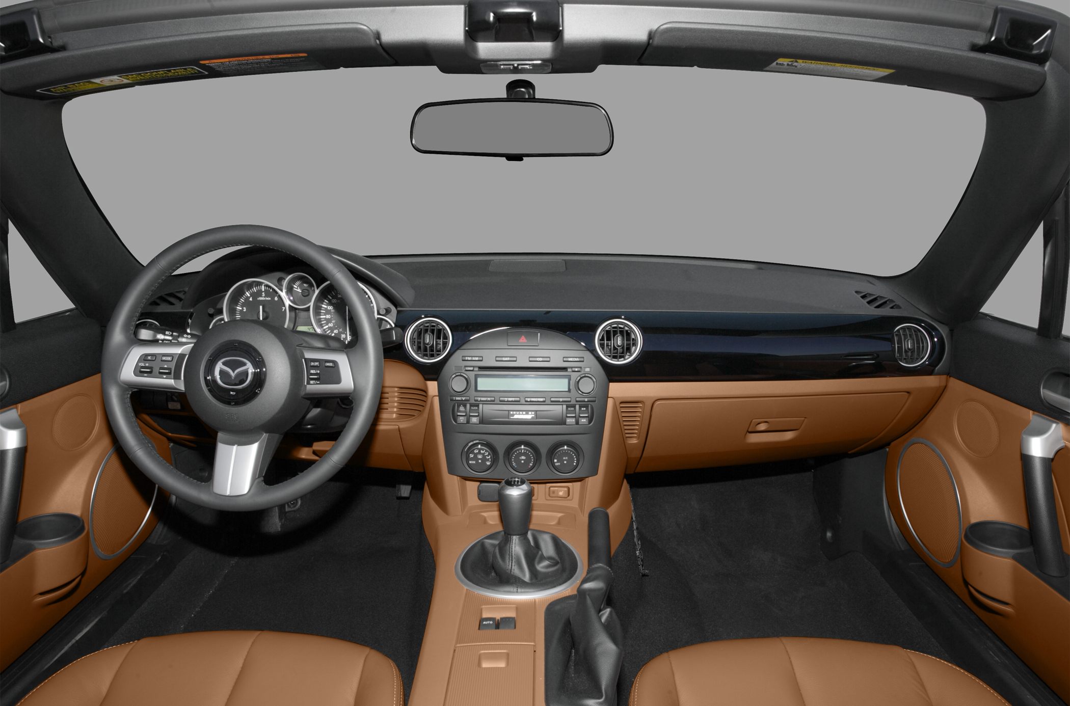Car interior with dashboard, steering wheel, and manual gear shift in brown upholstery.