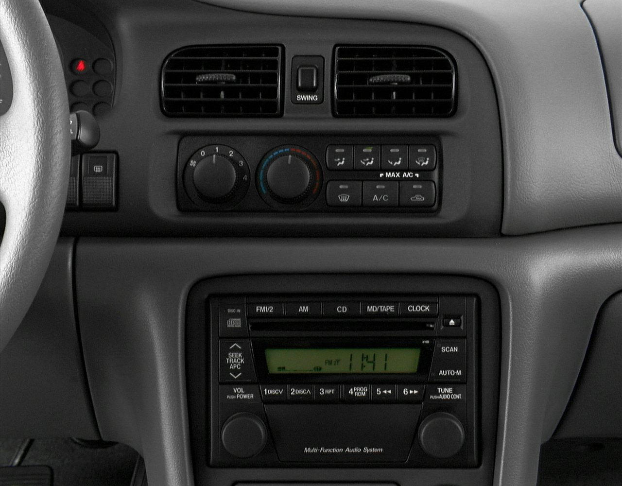 Dashboard air vents and vintage multi-function audio system with cassette player.