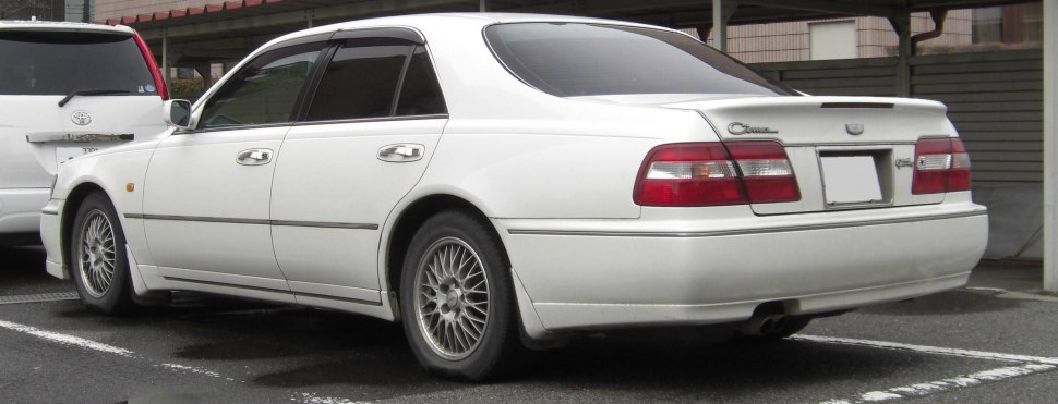 White sedan with rear spoiler and mesh alloy wheels