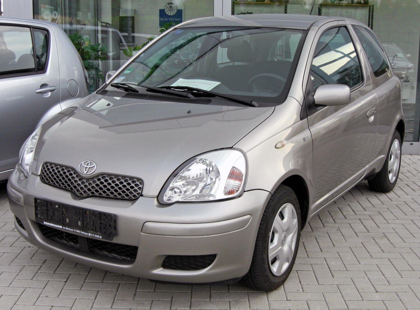 Silver compact 3-door hatchback front view with clear headlights and grille.