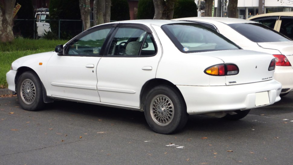 White sedan with wire-spoke wheels and rounded rear lights, mid-1990s design.