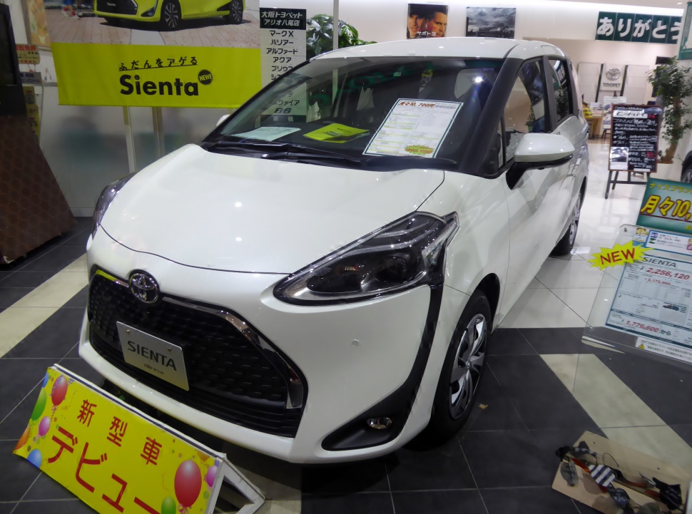 Front grille and side profile of white compact MPV in showroom