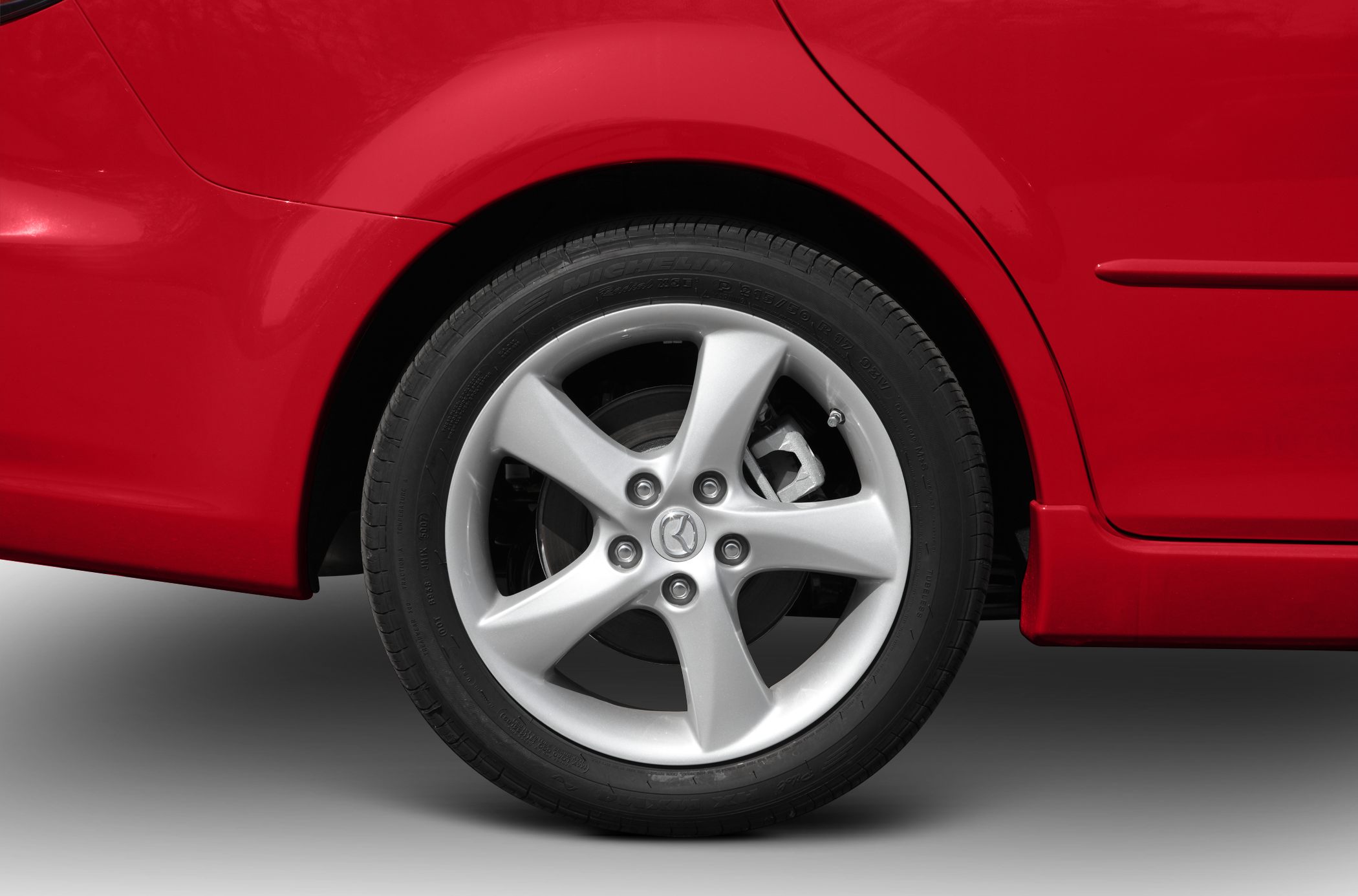 Close-up of 5-spoke alloy wheel and Michelin tire on red vehicle