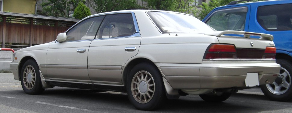 Rear side view of a 1990s four-door sedan with alloy wheels and rear spoiler