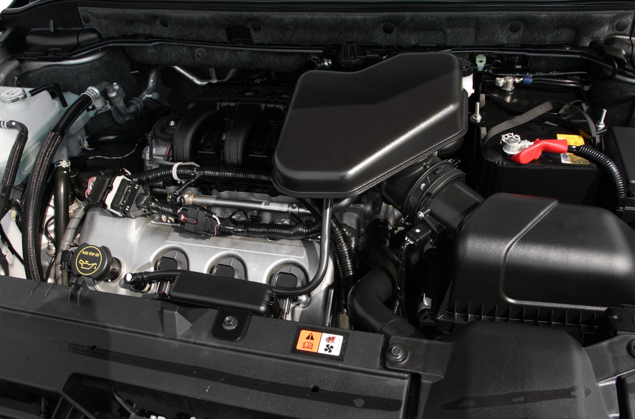 Detailed engine compartment with air intake, oil cap, battery, wiring harness.