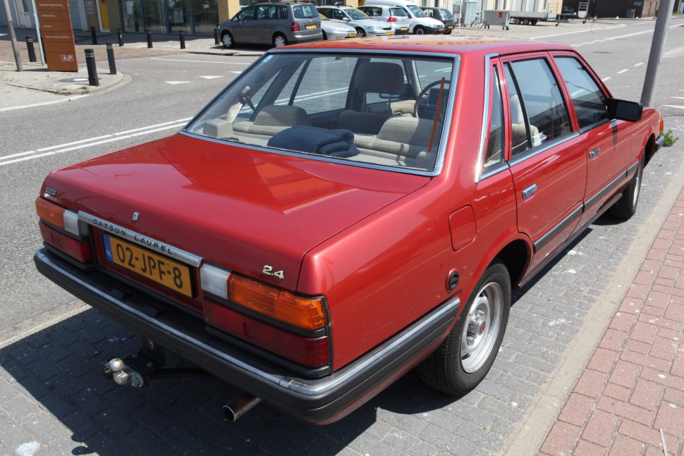 Rear and side view of red 1980s four-door sedan with vintage tail lights and chrome trims