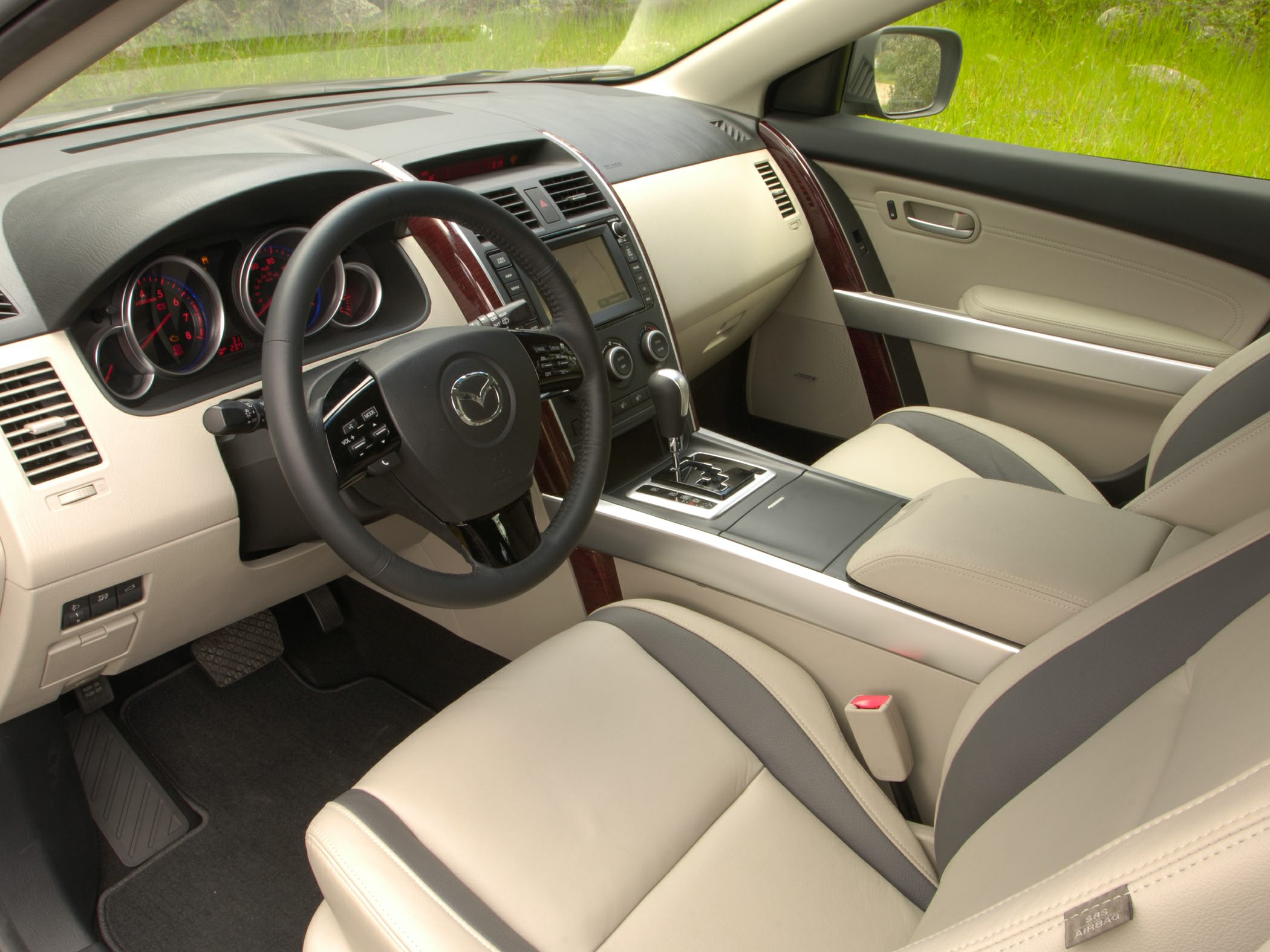 Dashboard, steering wheel, beige leather front seats, wood trim accents