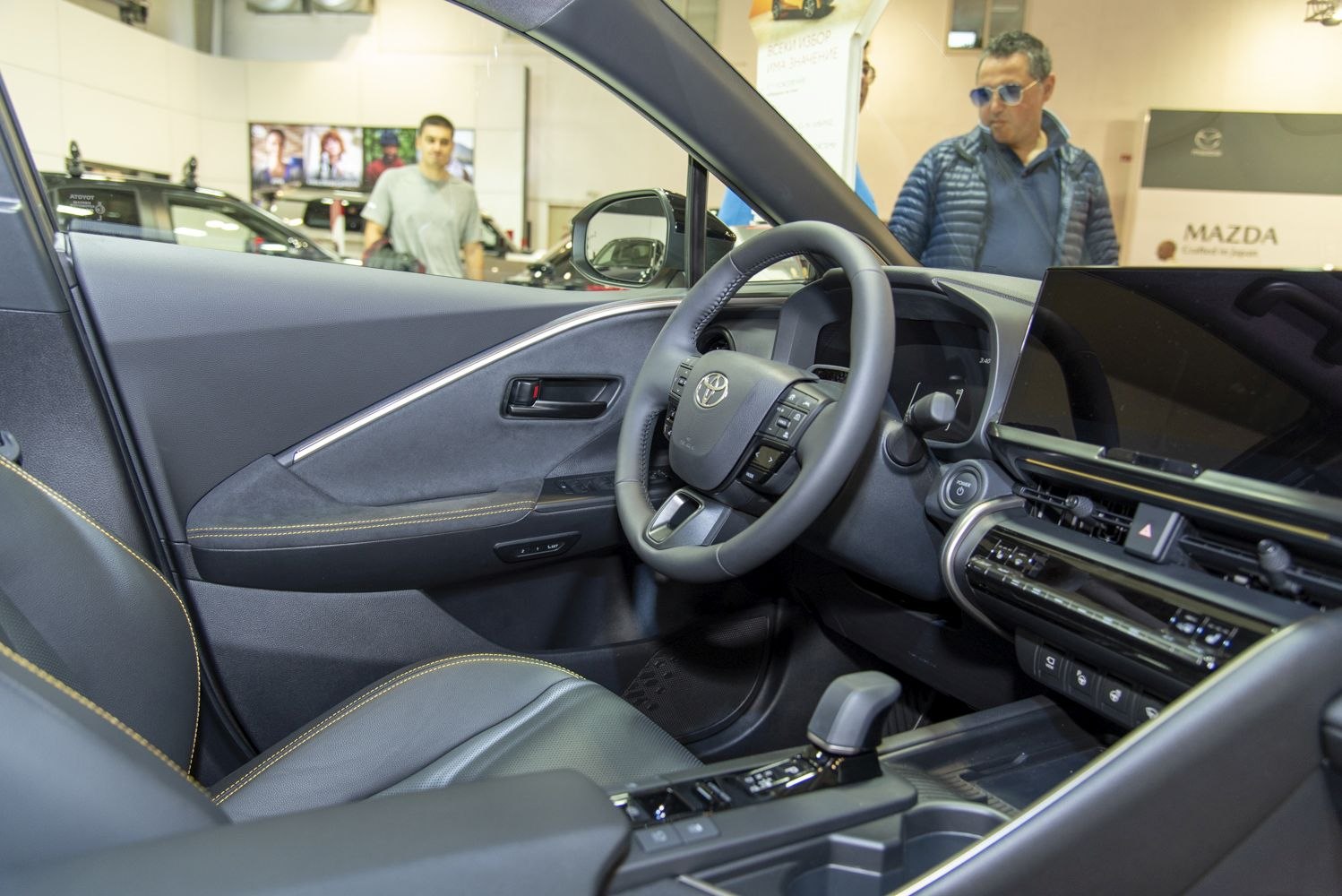 Leather steering wheel and modern digital dashboard with touchscreen display.
