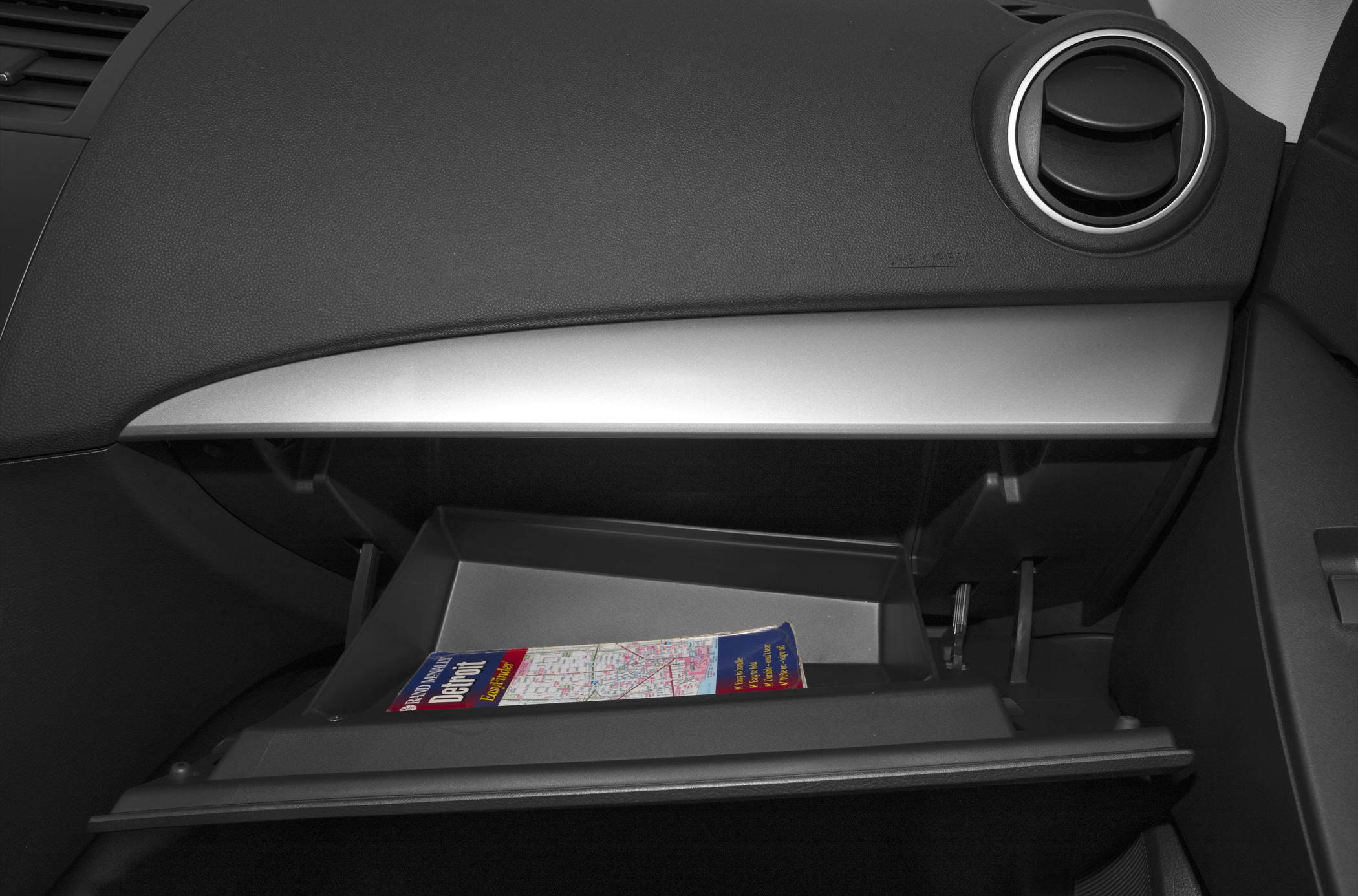 Open glove compartment with map inside on sedan dashboard