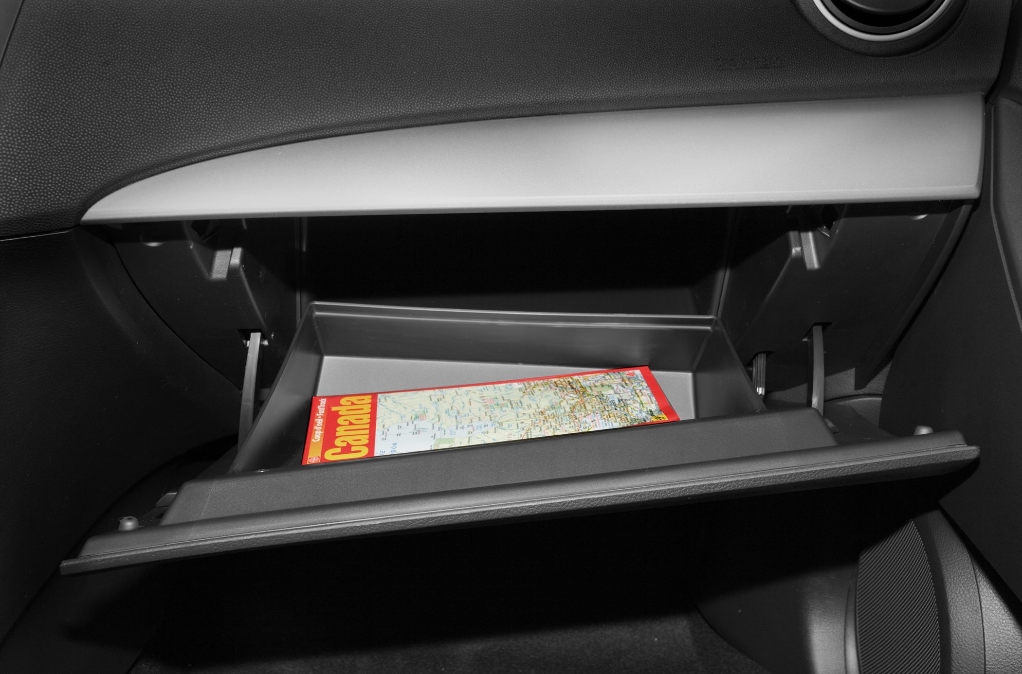 Open glove box storage compartment with a map inside