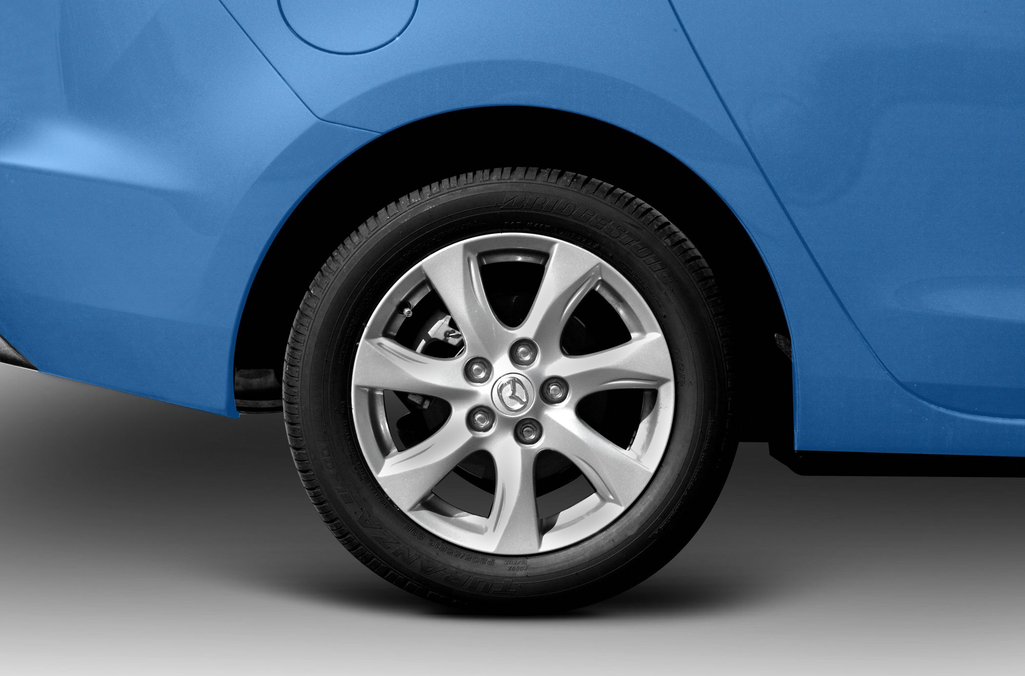 Alloy wheel rim and tire on rear side of blue sedan
