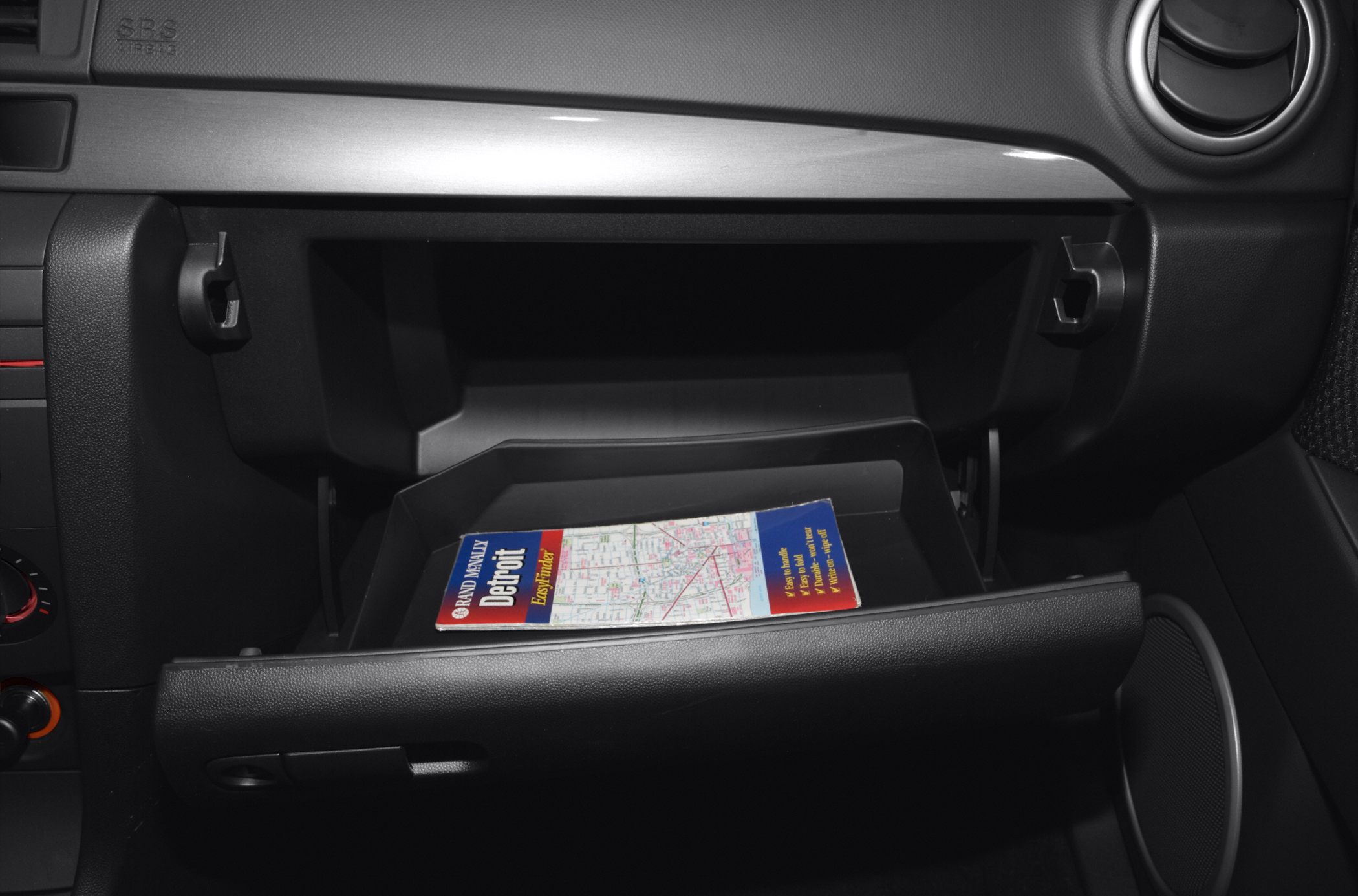 Open glove box interior with a map inside