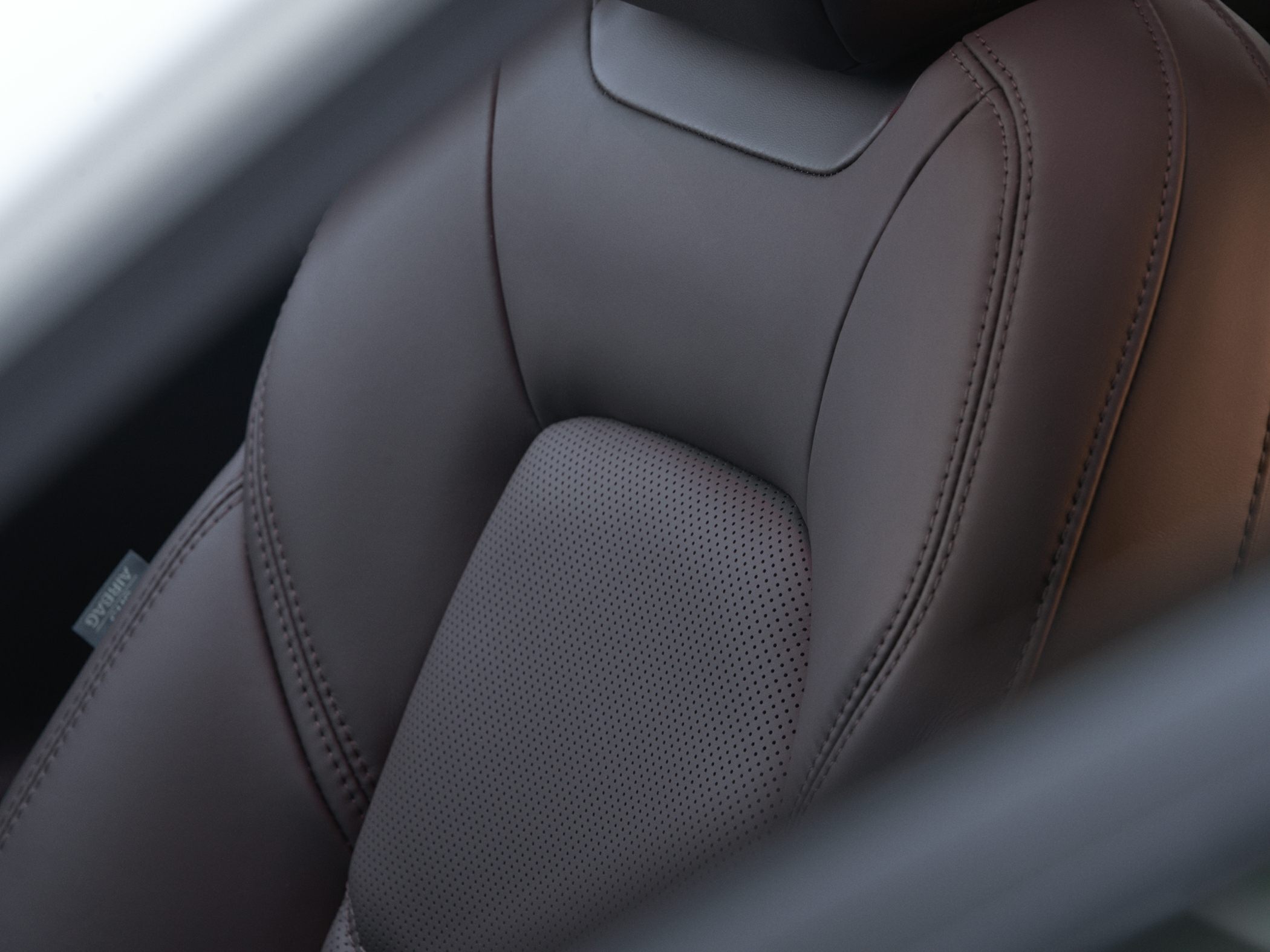 Close-up of leather car seat with perforated center and stitched detail