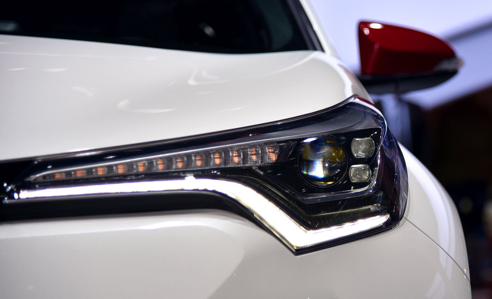 Close-up of sharp LED projector headlight and red side mirror