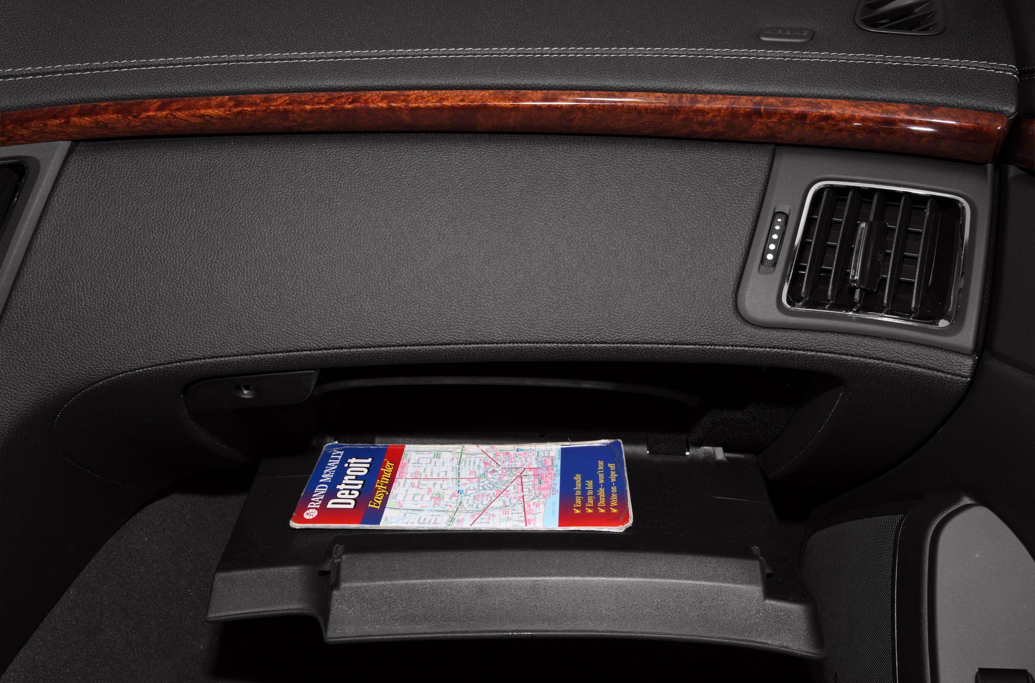 Glove compartment with map and adjacent air vent in a car interior