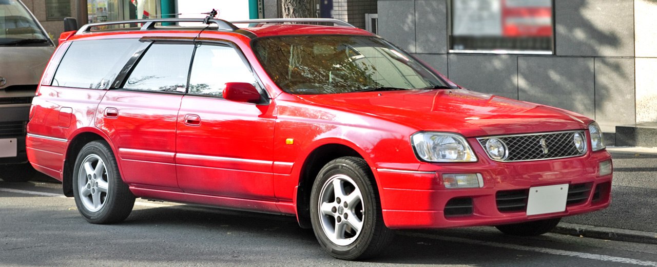 Red station wagon with alloy wheels, roof rails, front-side view