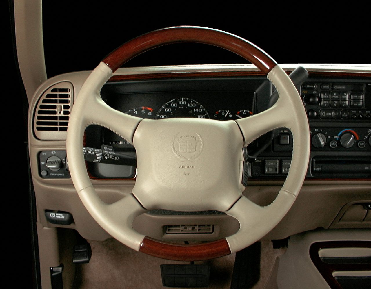 Beige and wood-trimmed steering wheel with dashboard gauges and controls.
