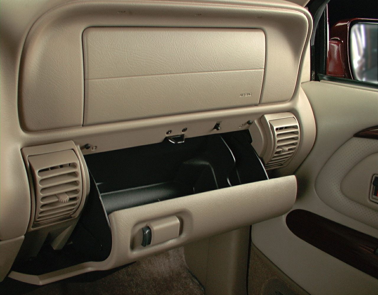Open glove compartment and dashboard air vents in tan interior