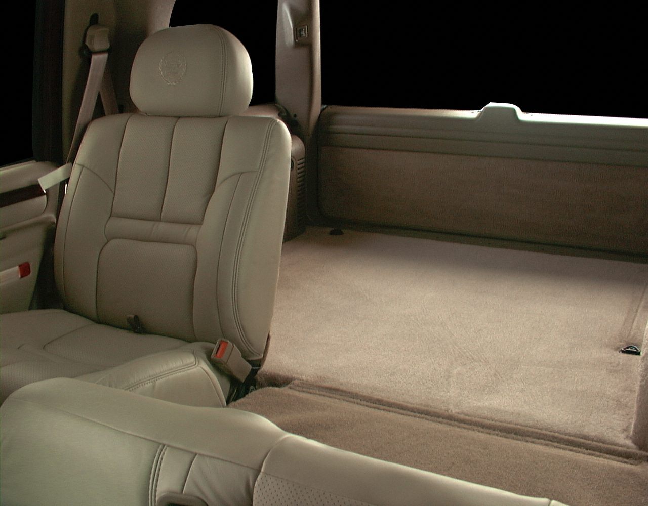 Beige leather SUV seat and large carpeted cargo area.