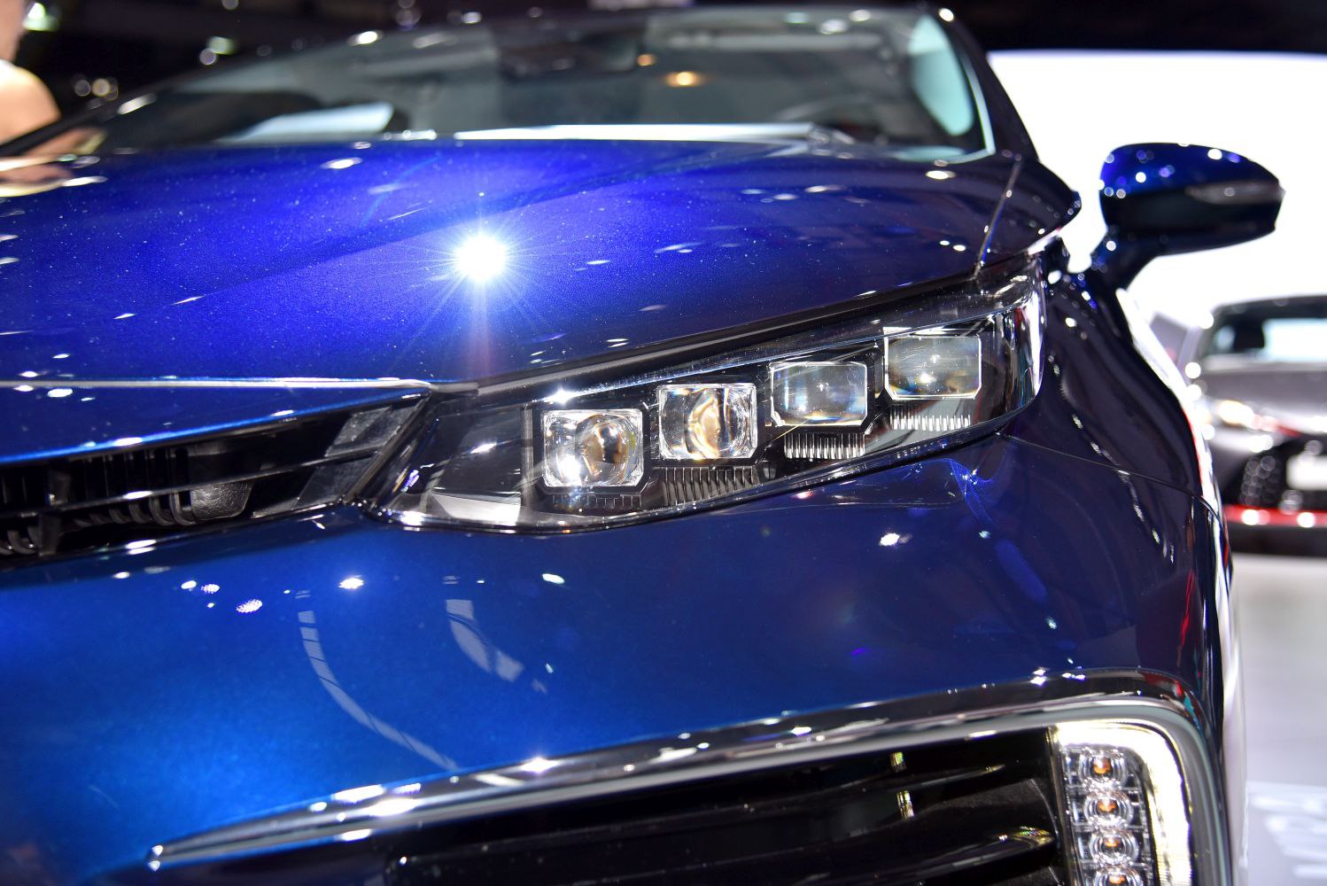 Sharp LED headlights and glossy blue hood with reflections.