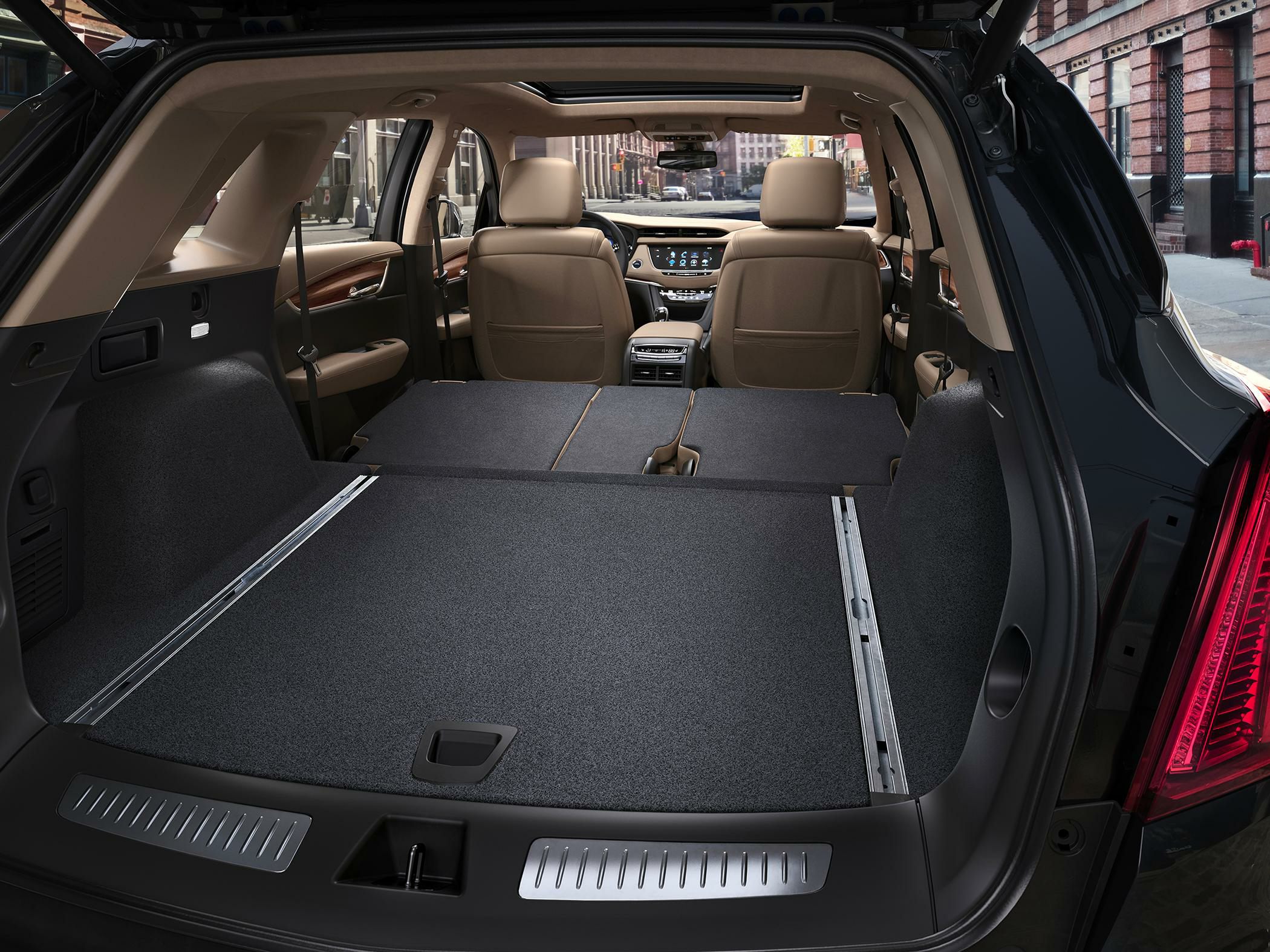 Folded rear seats creating extended cargo space with beige leather seats and panoramic sunroof.
