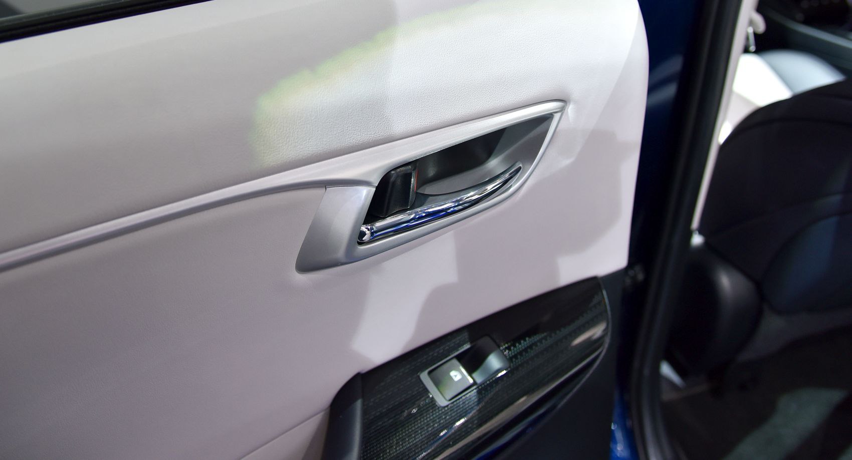 Close-up of car interior door handle and window control panel