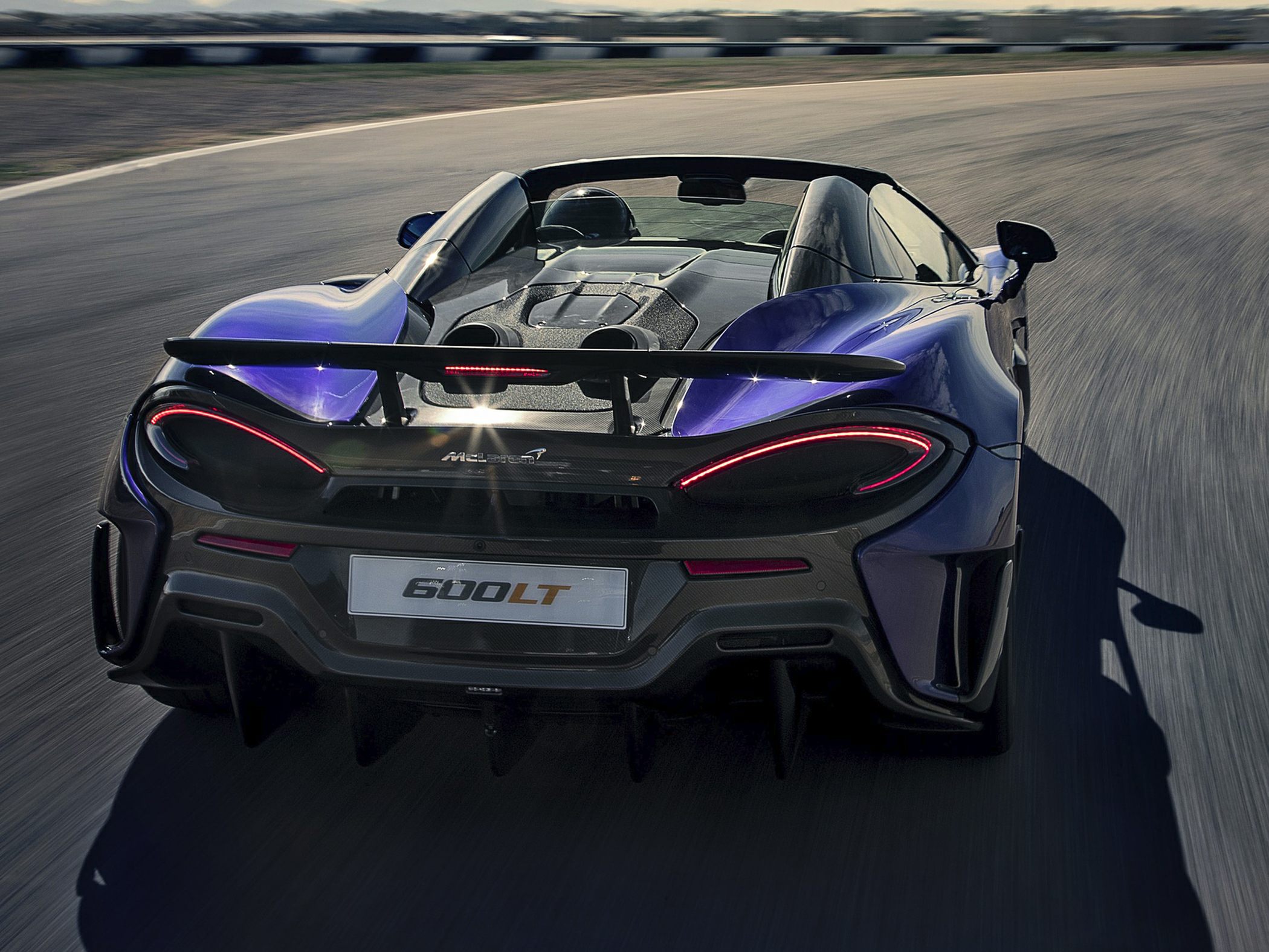 Rear view featuring active spoiler and sleek taillights on a convertible sports car.
