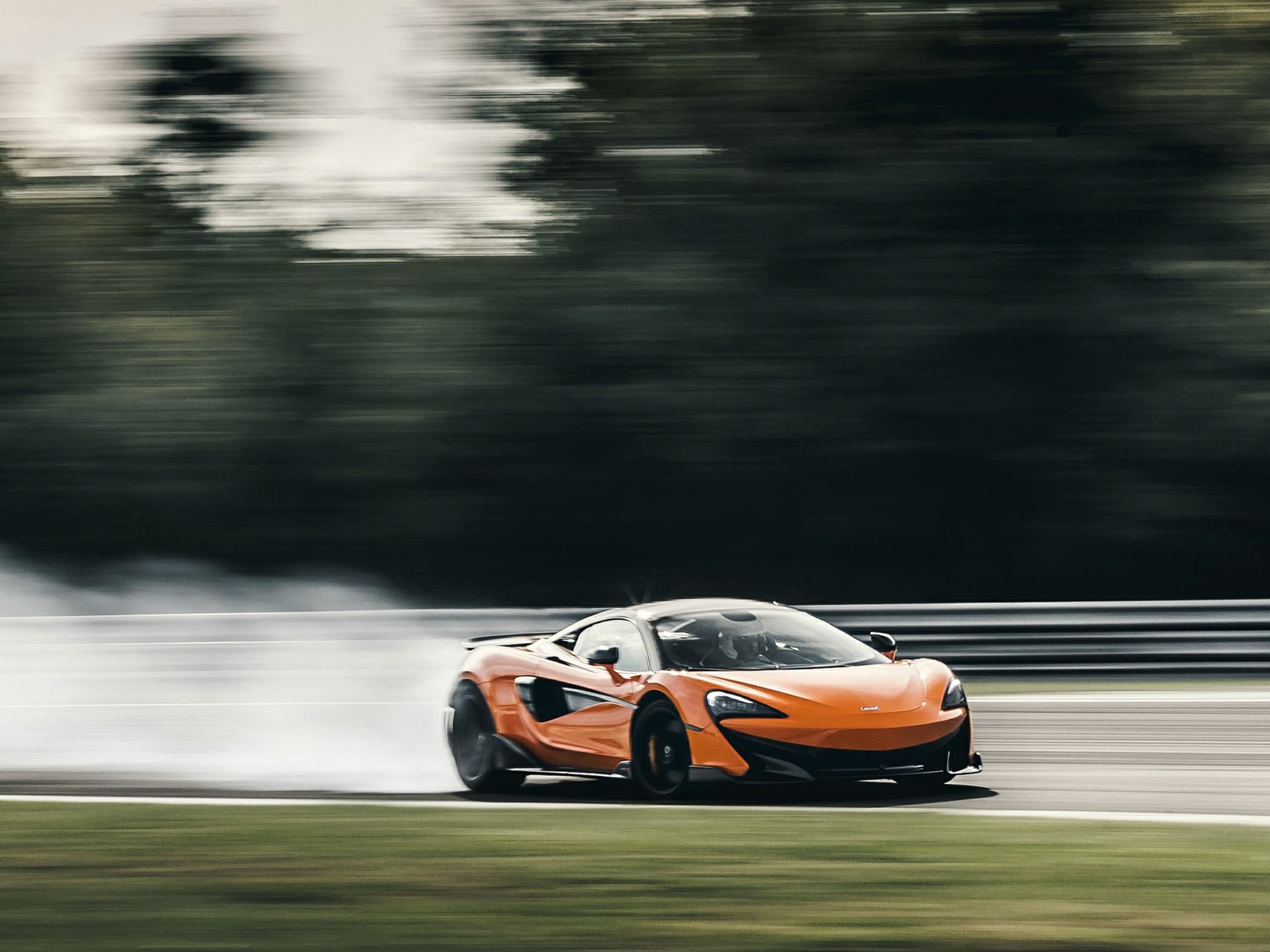 High-speed drifting of an orange sports coupe on a racetrack