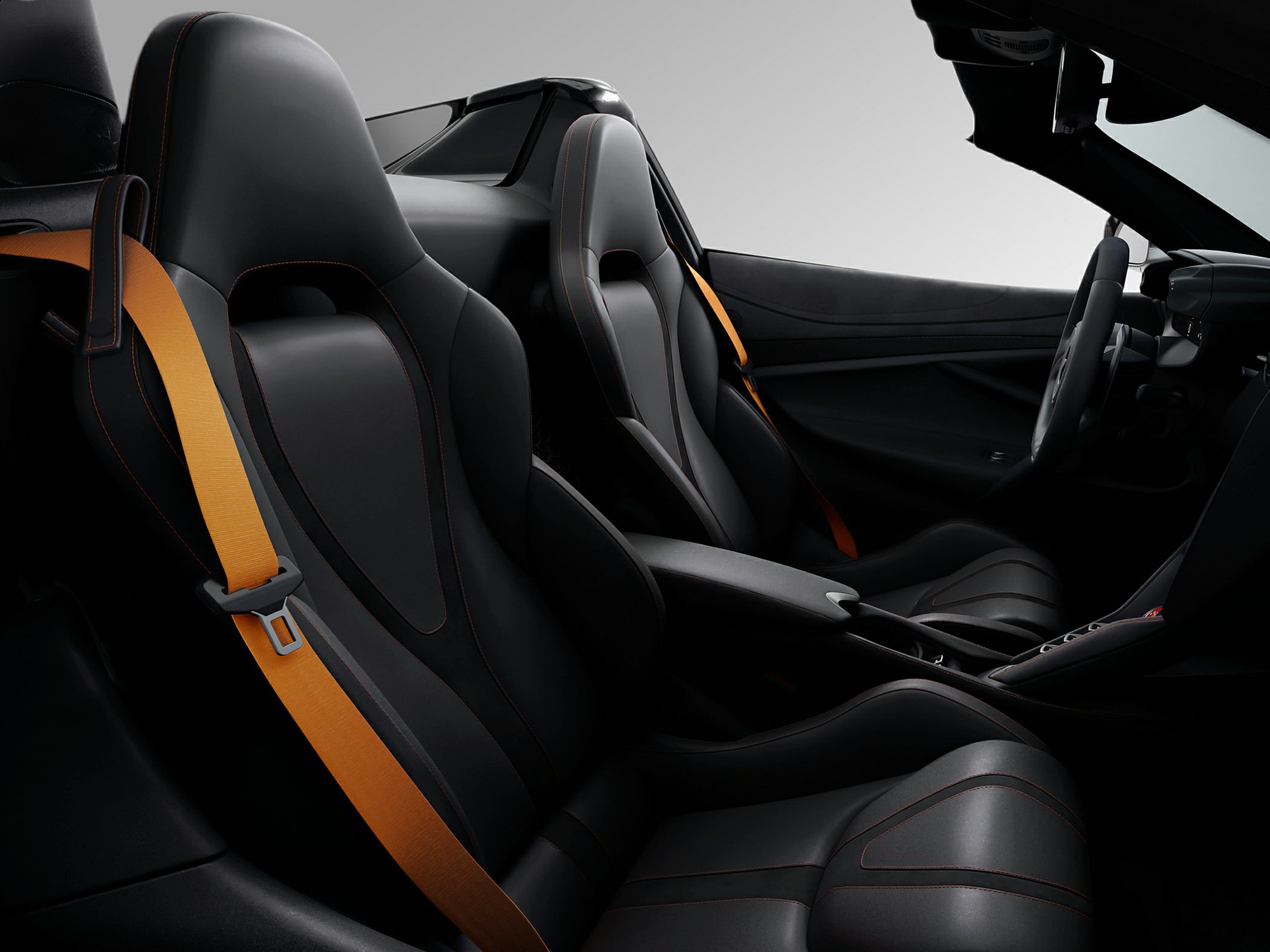 Black leather sport seats with orange seat belts in luxury car interior