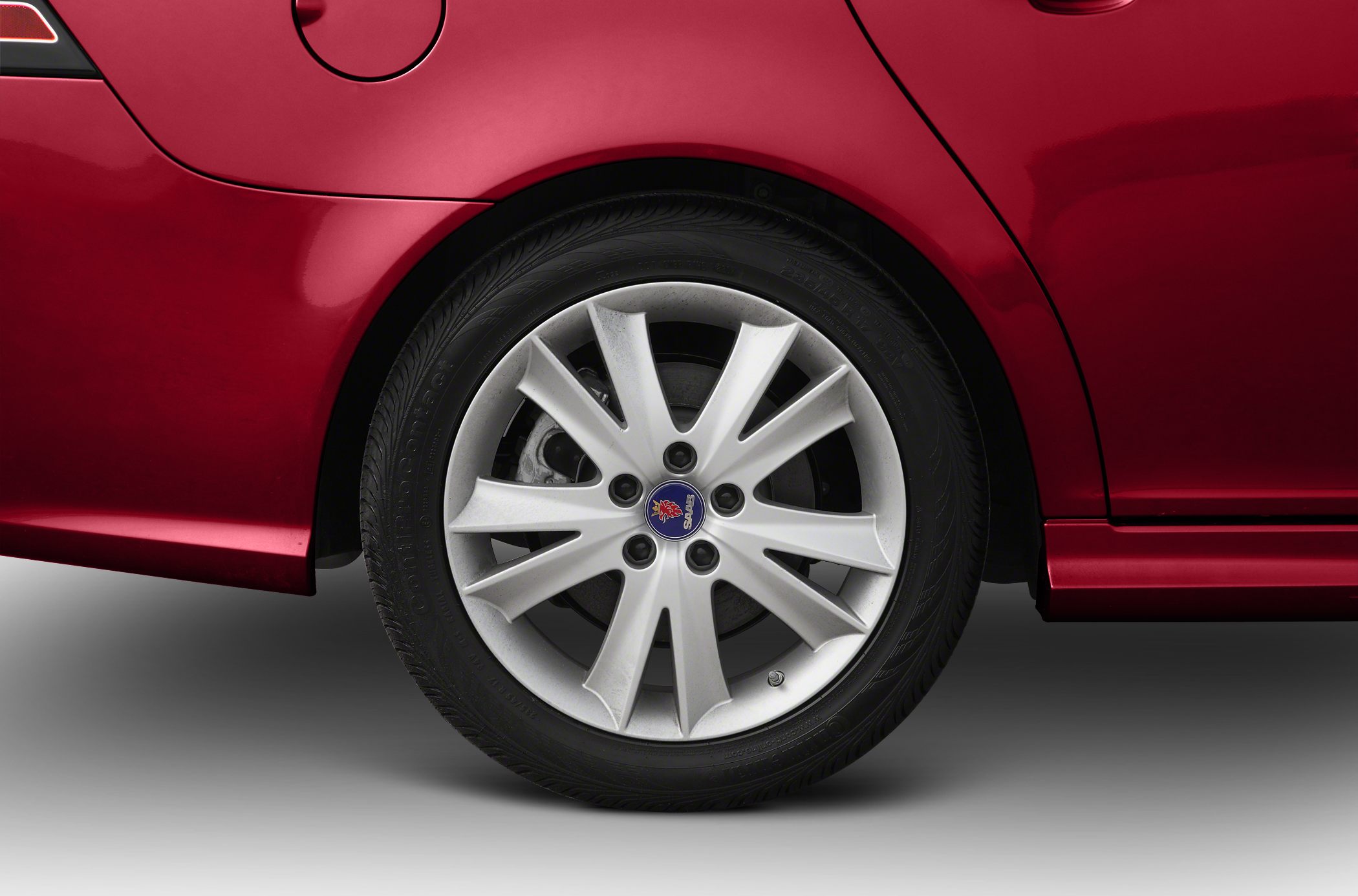 Close-up of alloy wheel with Saab emblem on red body.