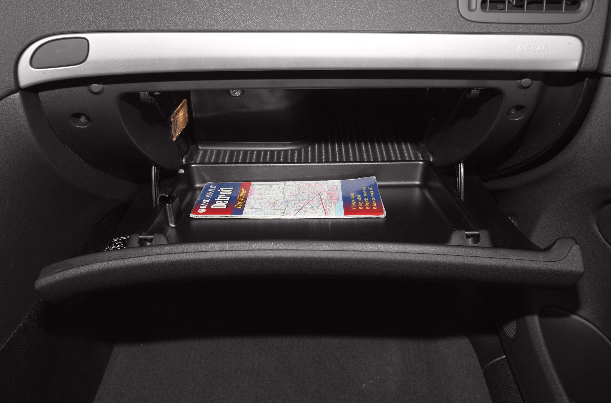 Open glovebox compartment with a map inside the car dashboard