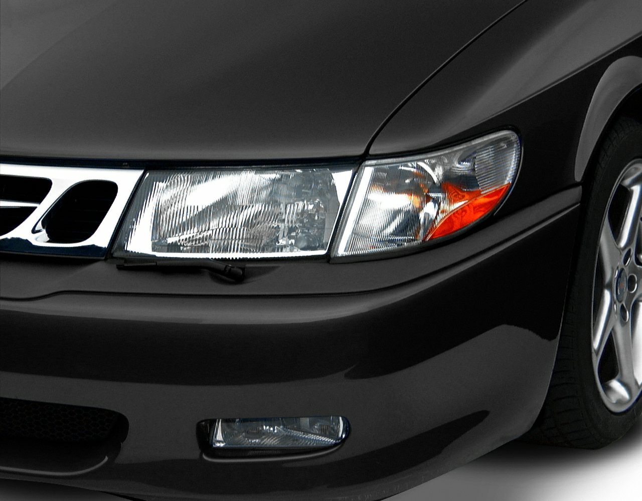 Close-up of car front headlight, bumper, and alloy wheel