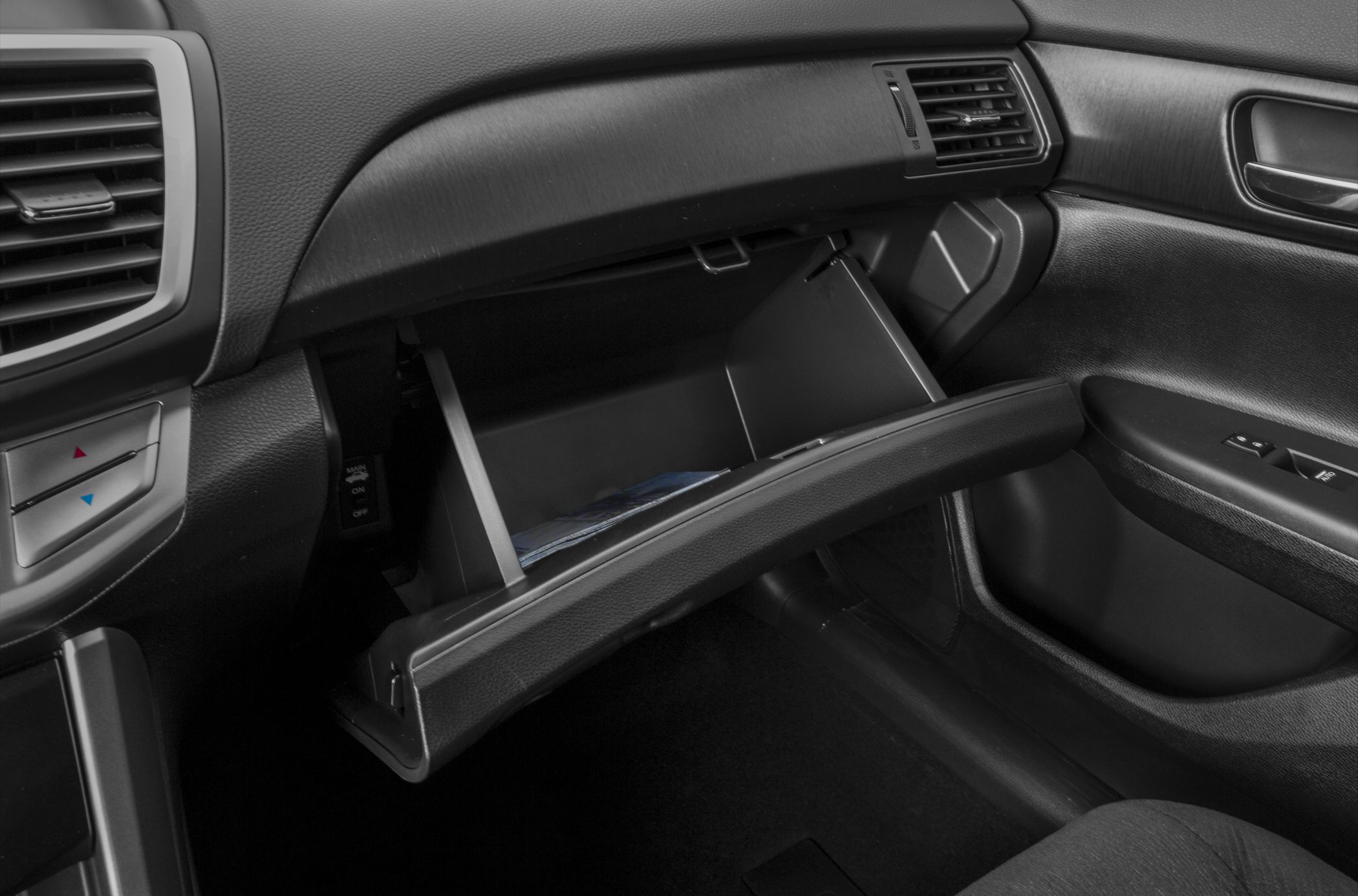 Open glove compartment with divided sections in black textured dashboard interior.