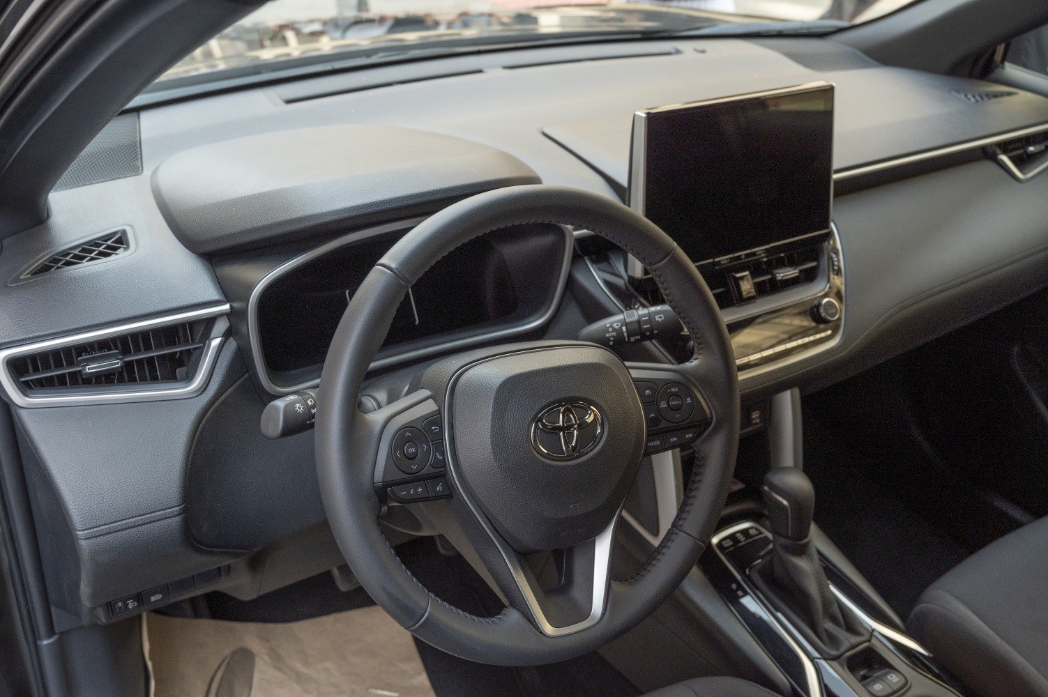 Modern steering wheel and dashboard with central touchscreen infotainment.