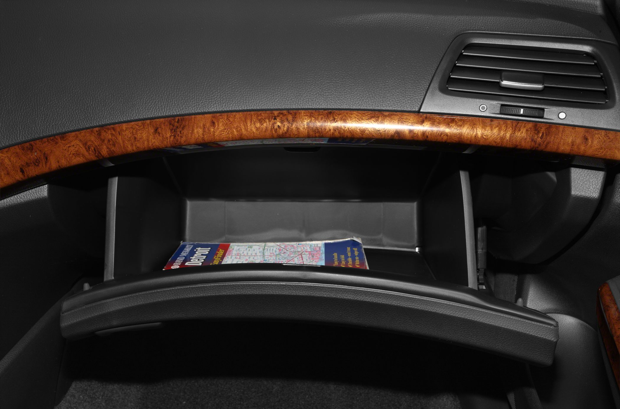 Open glove compartment with wood trim and a map inside