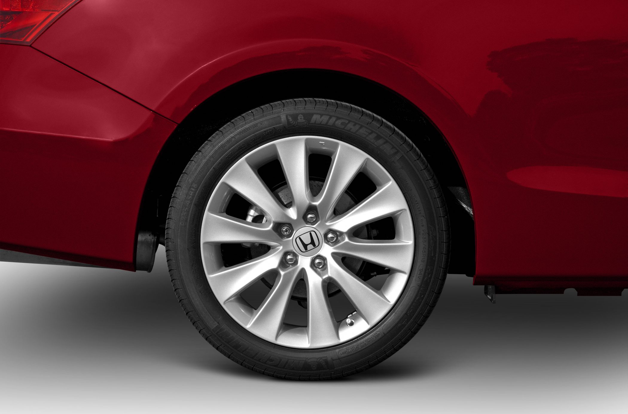 Close-up of alloy wheel and Michelin tire on red car rear.