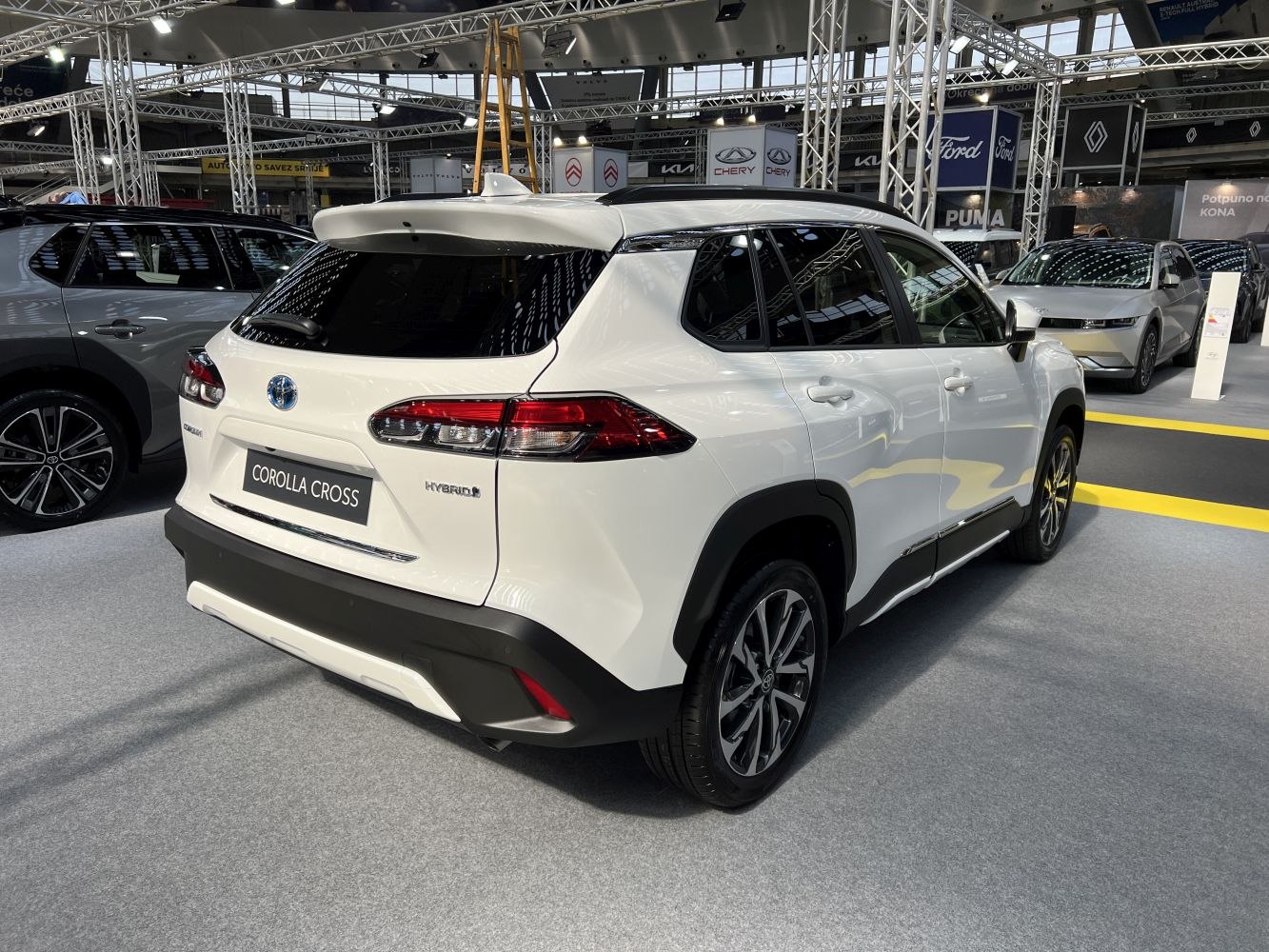 White hybrid SUV rear side with alloy wheels and roof spoiler
