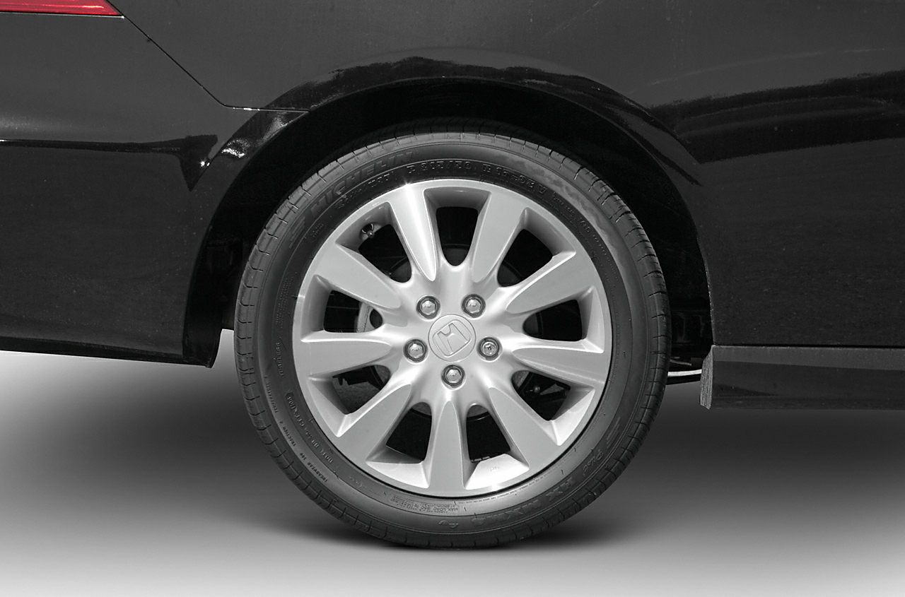 Close-up of multi-spoke alloy wheel with tire on car rear side.