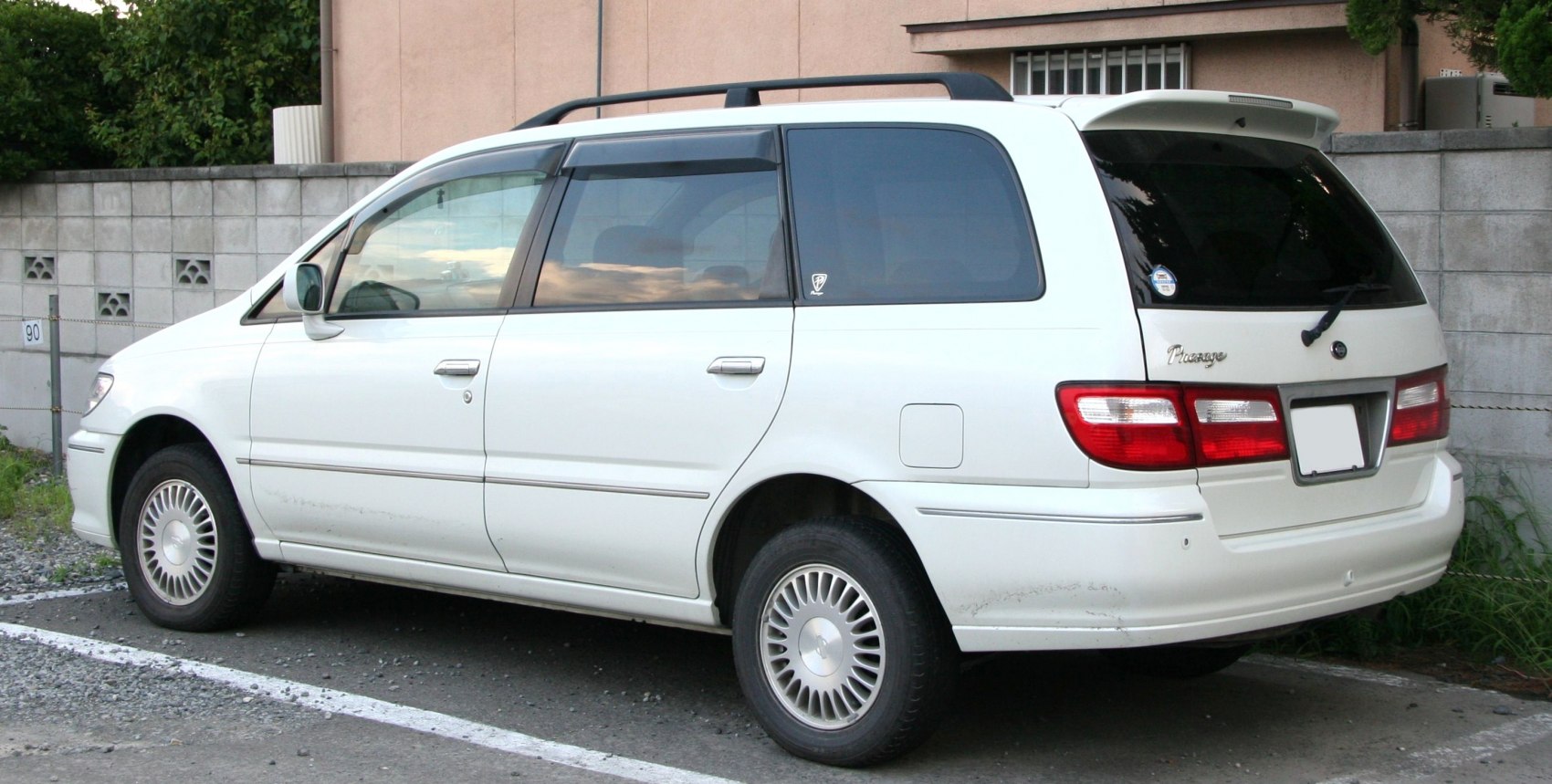 Side and rear view of white minivan with roof rails and distinct rear lights