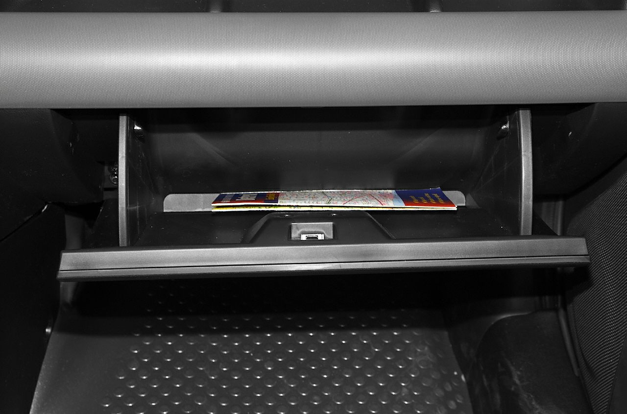 Open glove box with a map inside on a vehicle interior.