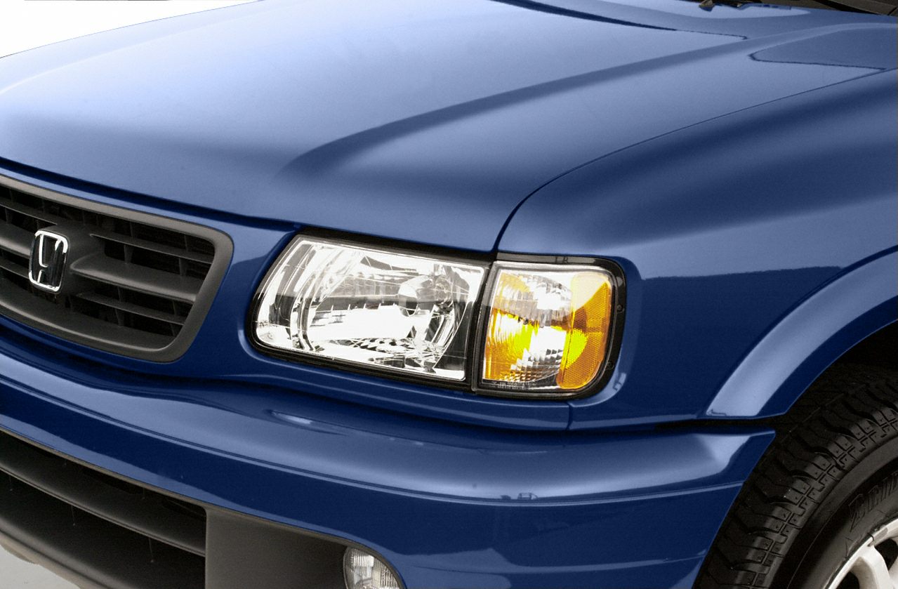 Front headlight with amber turn signal and black grille on blue vehicle