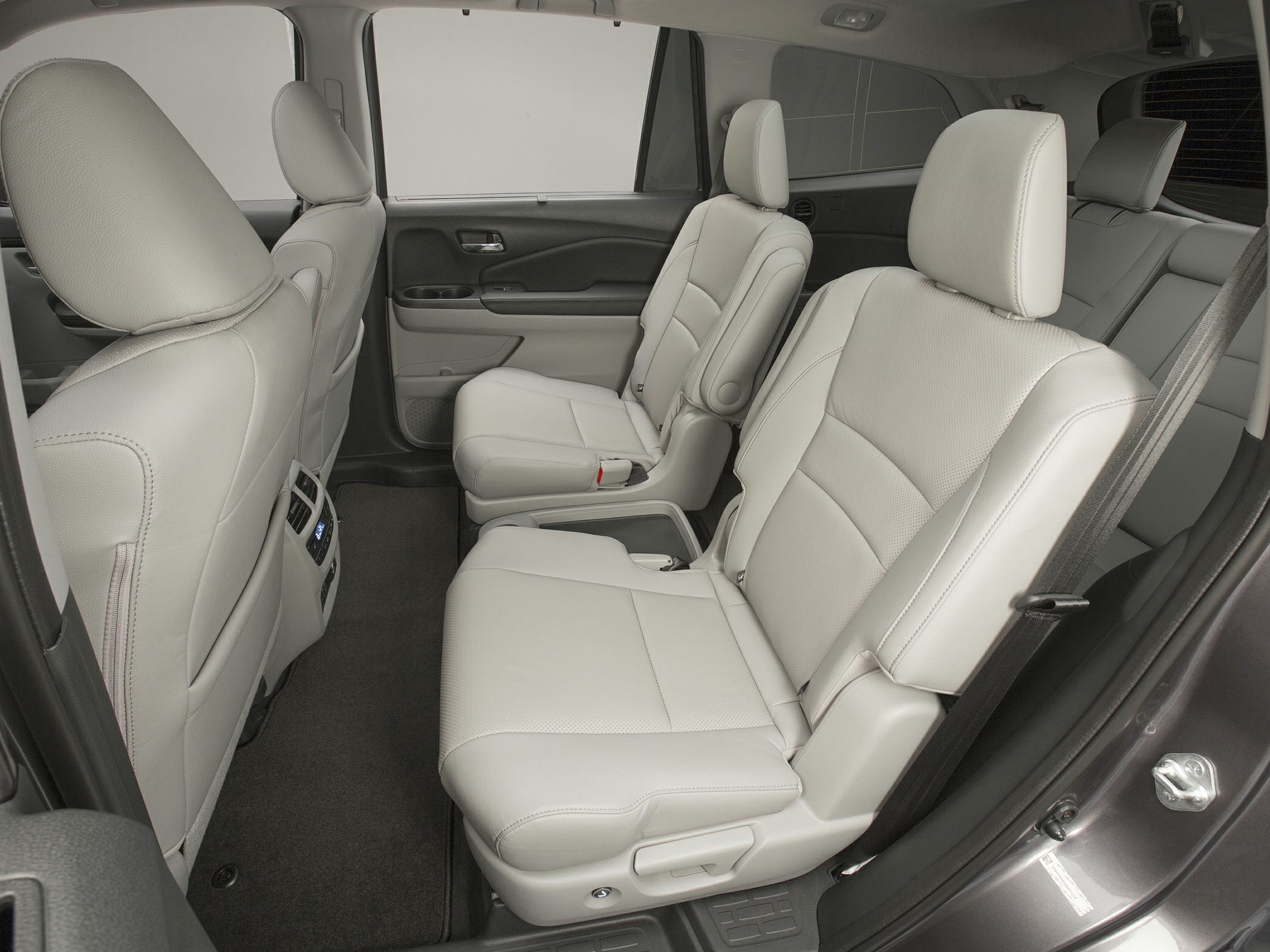 Spacious rear passenger seats with light leather upholstery and armrests