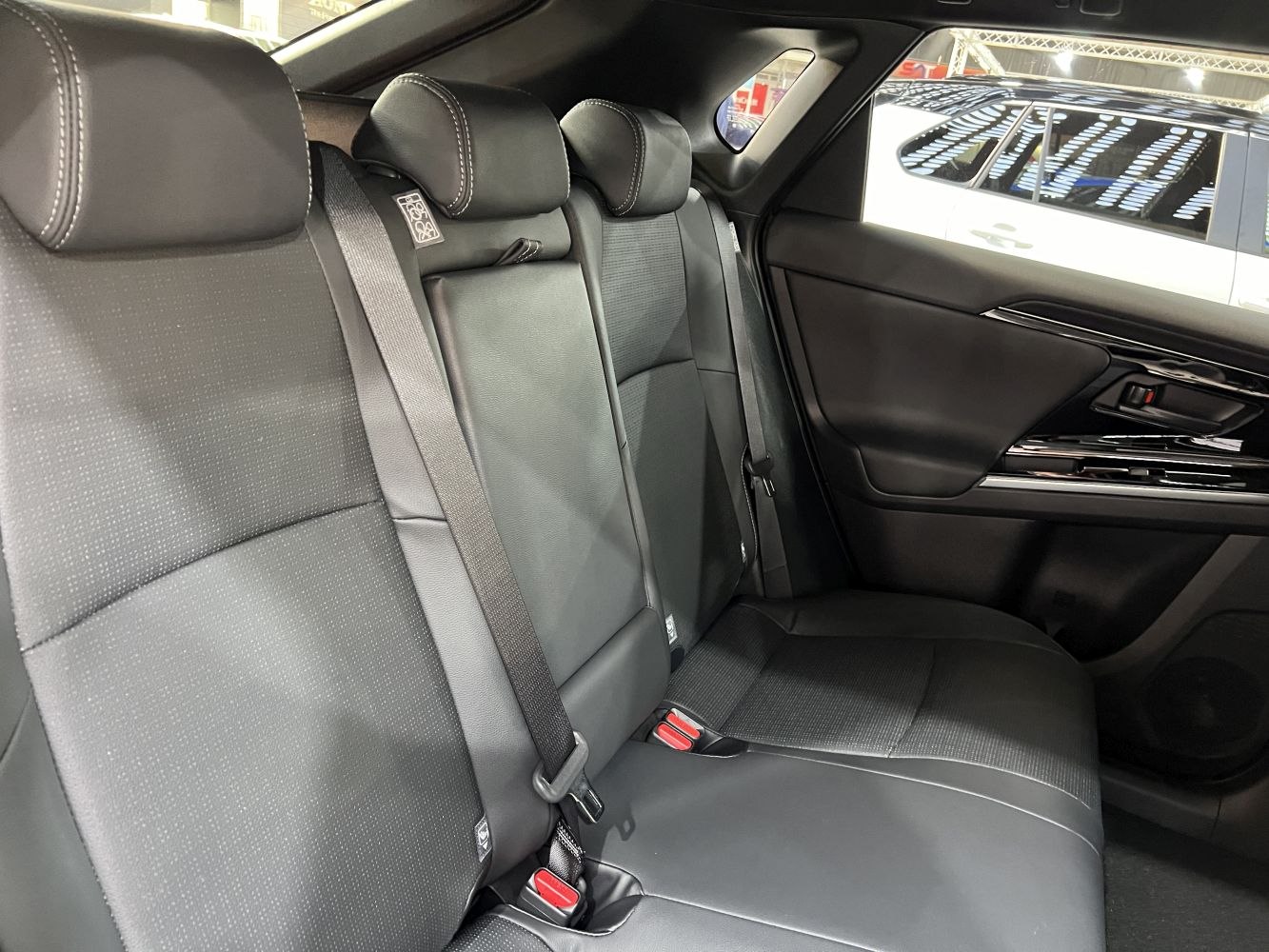 Rear seat with black upholstery, headrests, and seatbelts