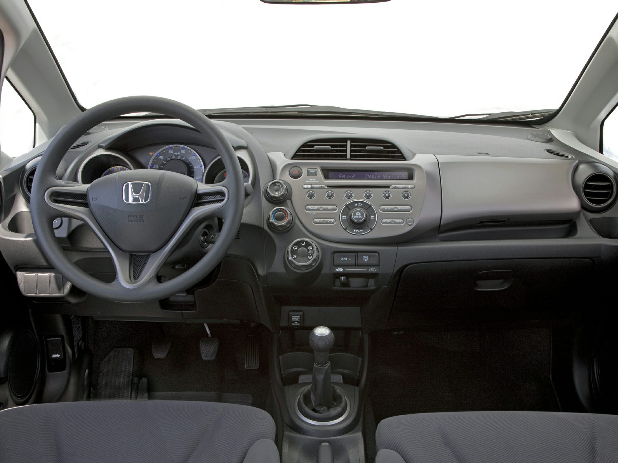 Steering wheel, dashboard, and manual gear shift in a compact car interior